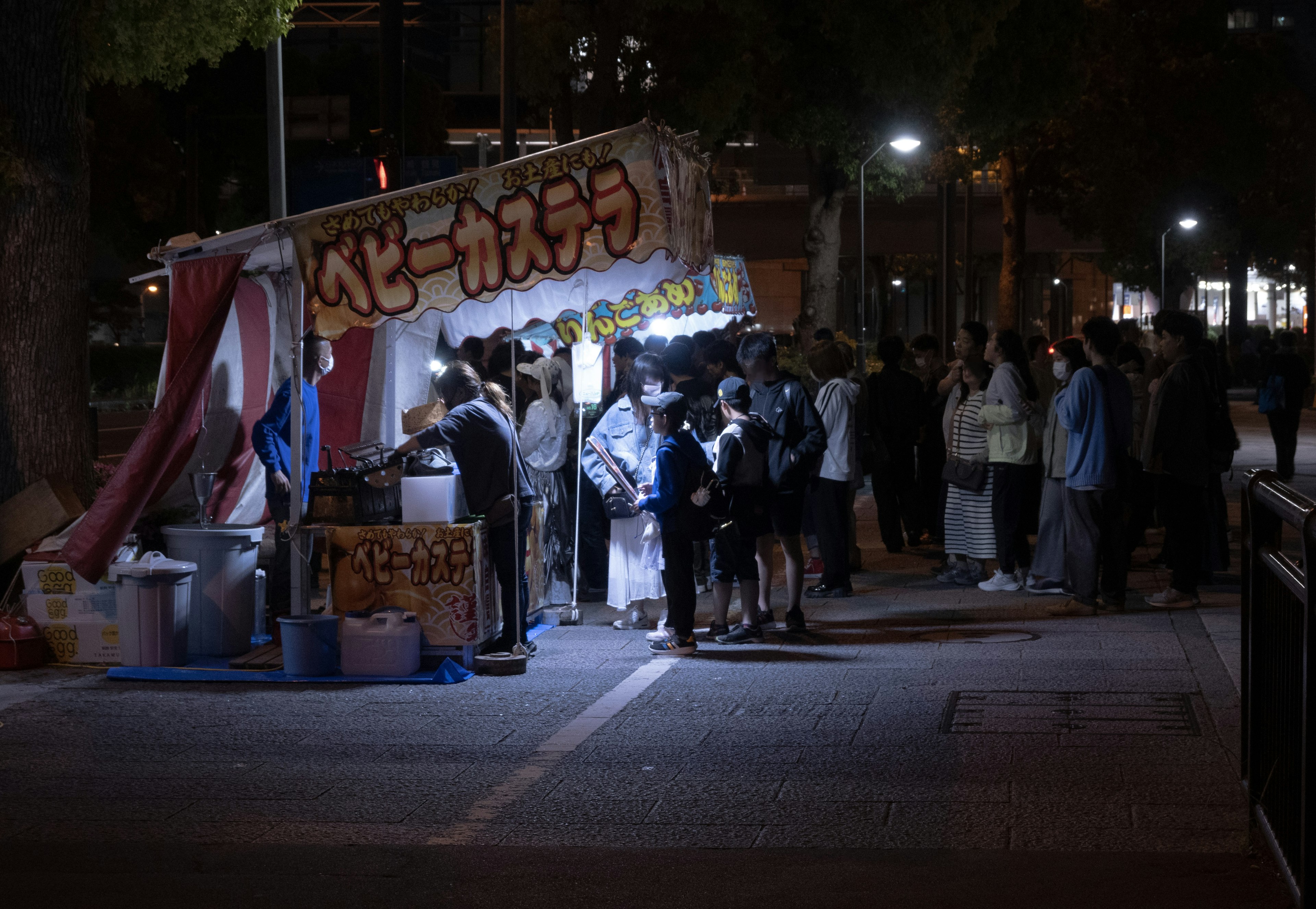 夜の屋台に並ぶ人々と明るい照明