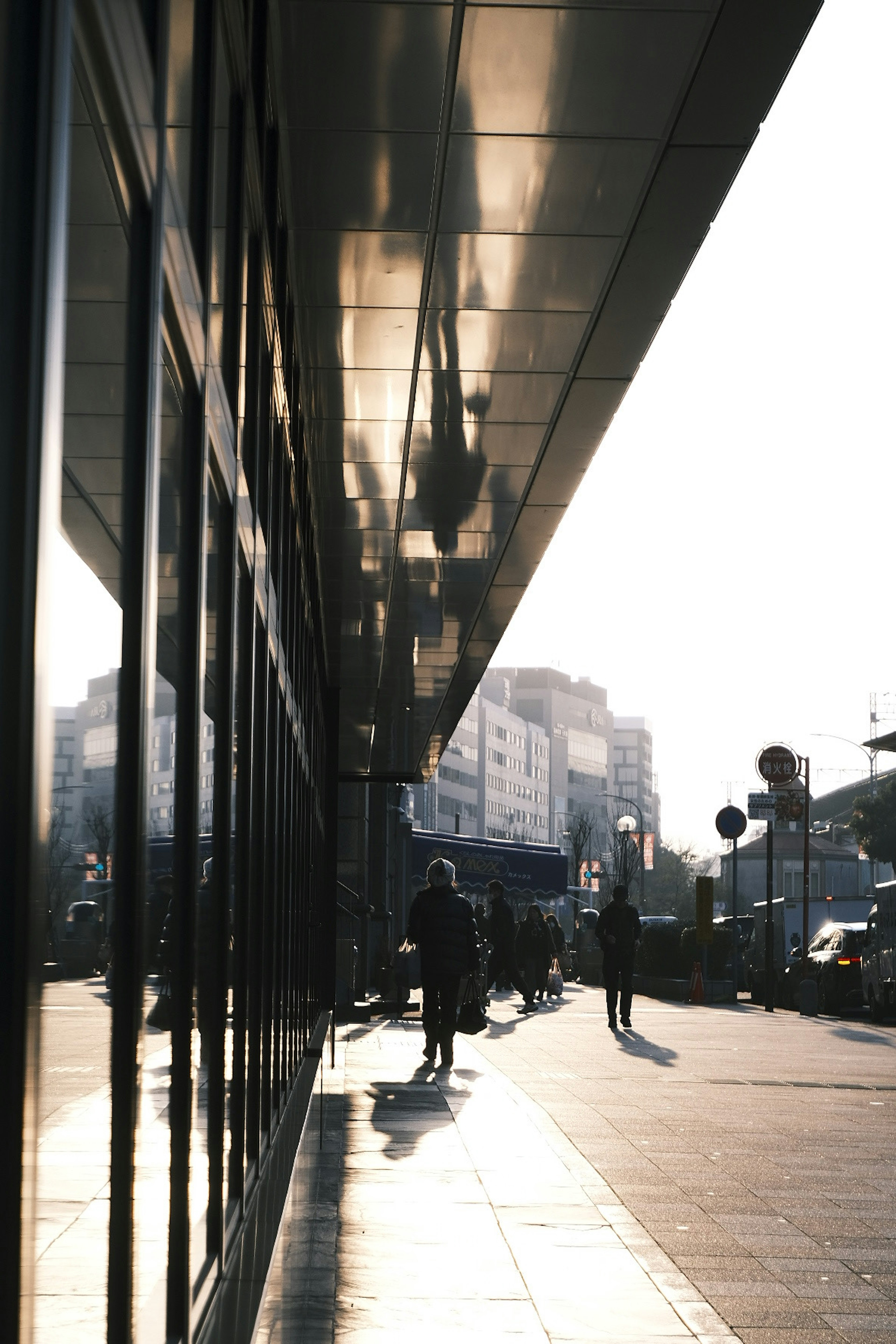 Urban scene with sunlight casting reflections on glass and people walking