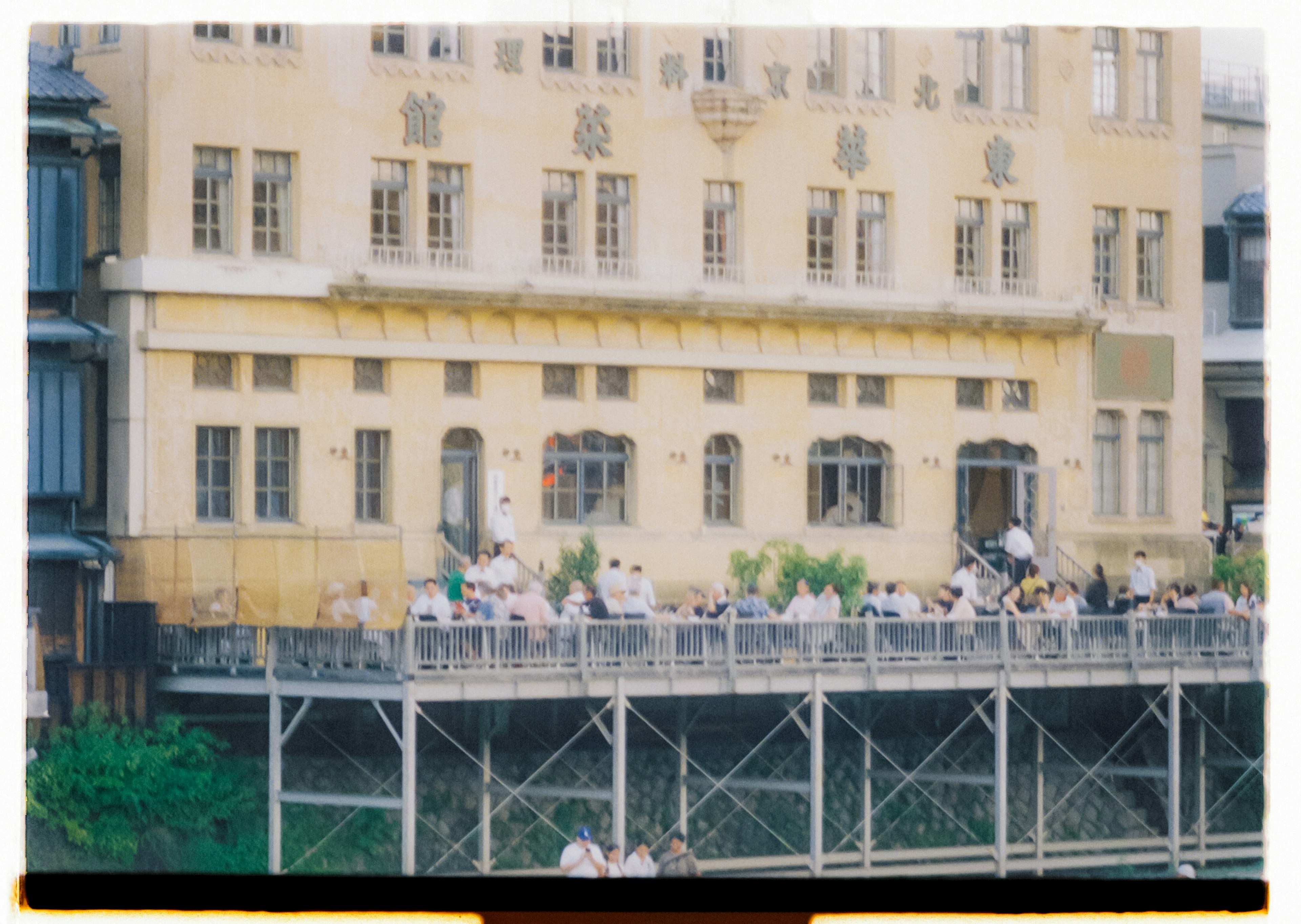 Edificio histórico con personas sentadas en una terraza junto al río