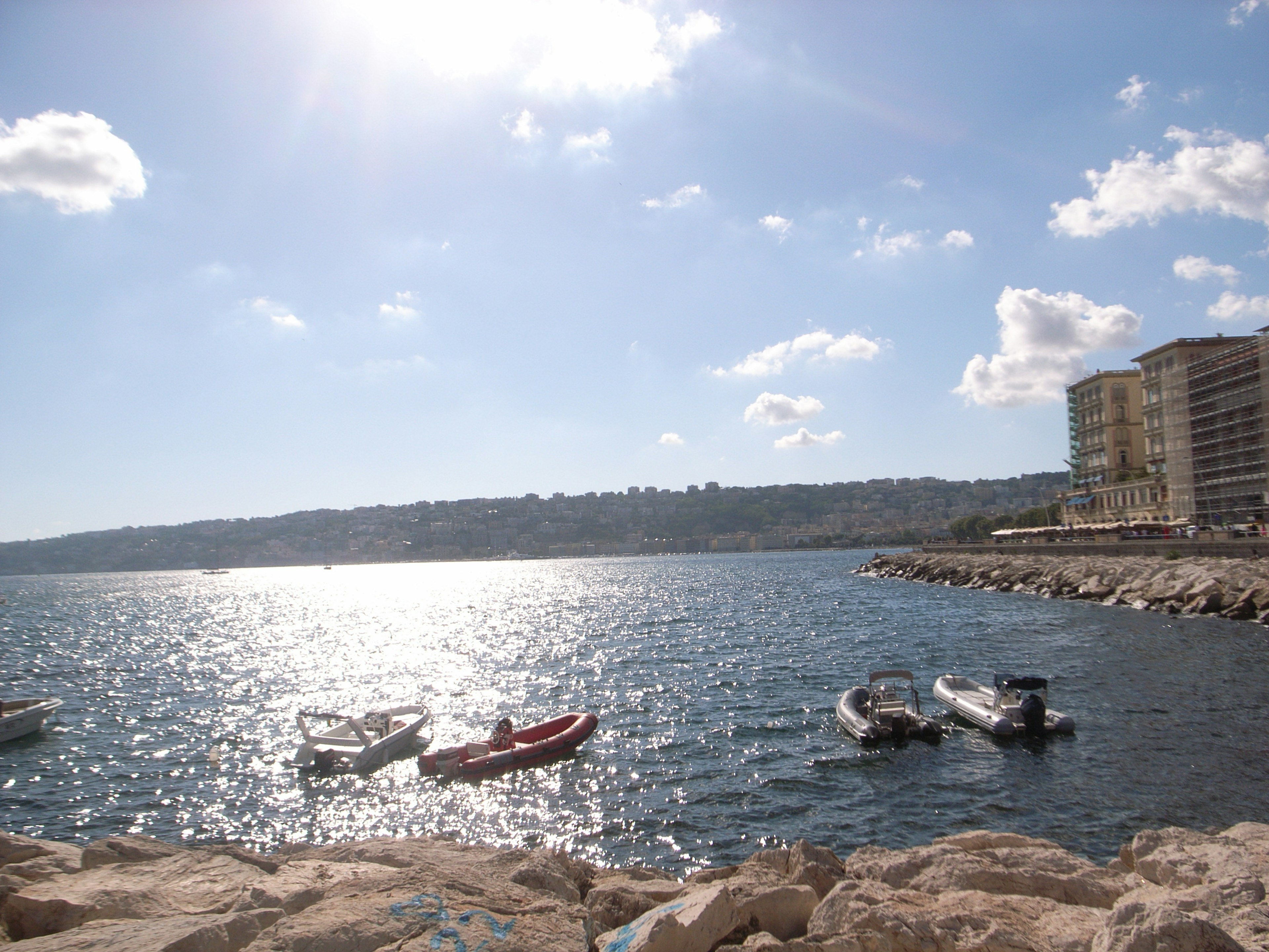 Scenic view of boats on a sparkling blue sea under a bright sky