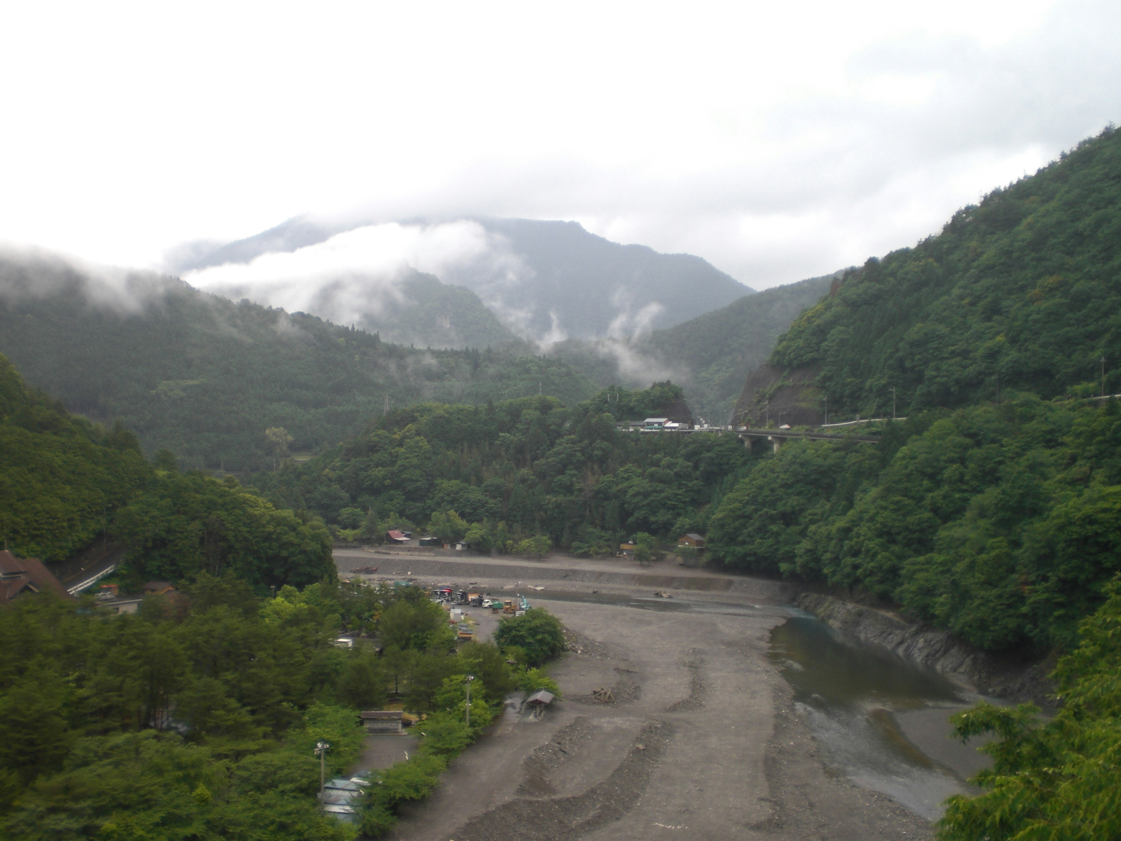 Paisaje montañoso brumoso con un río y vegetación exuberante