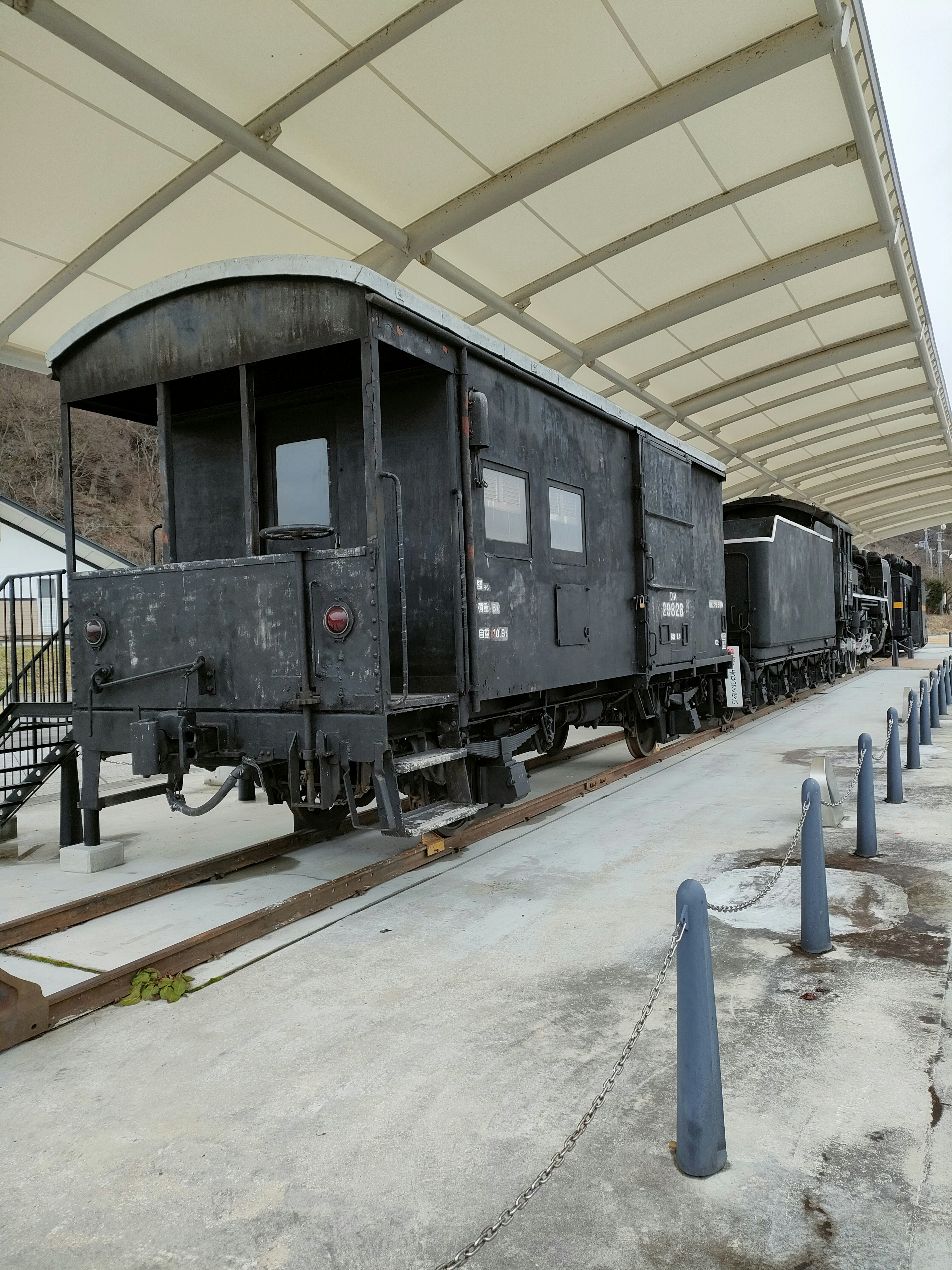 Ein alter schwarzer Güterwagen, der an einem Bahnhof parkt