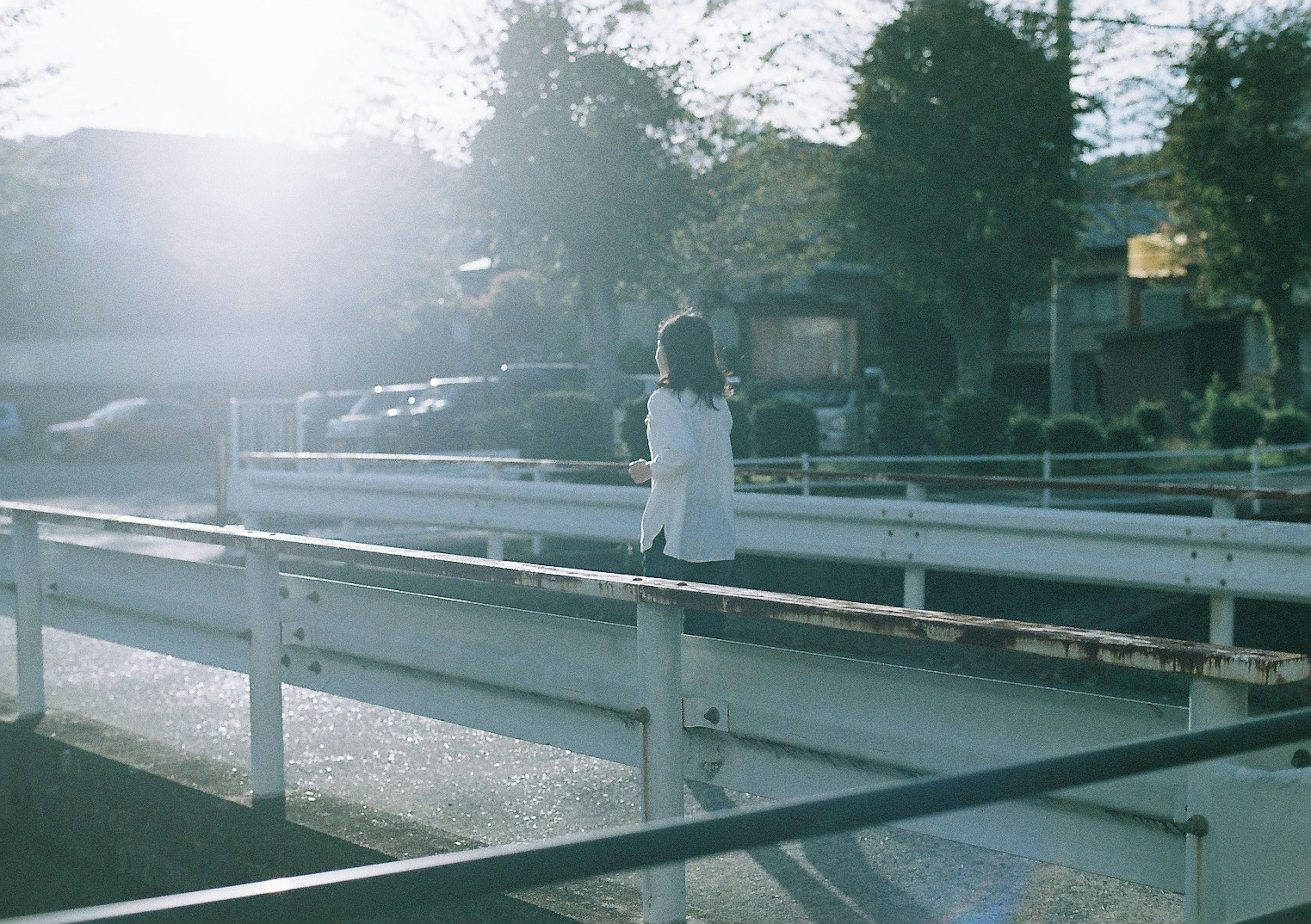 白い服を着た女性が明るい夕日を背にして歩く風景