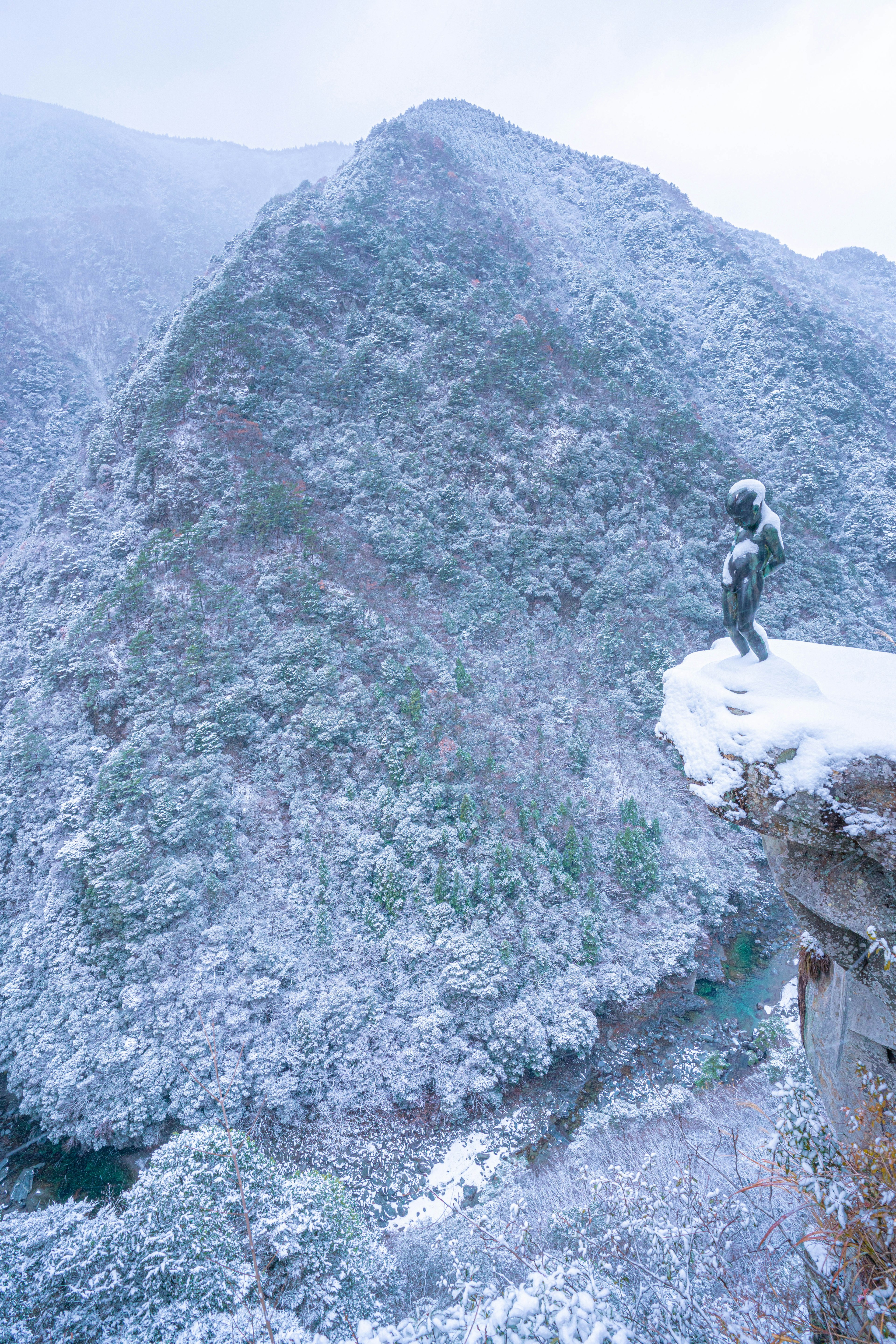 Snow-covered mountain landscape with a statue on the summit