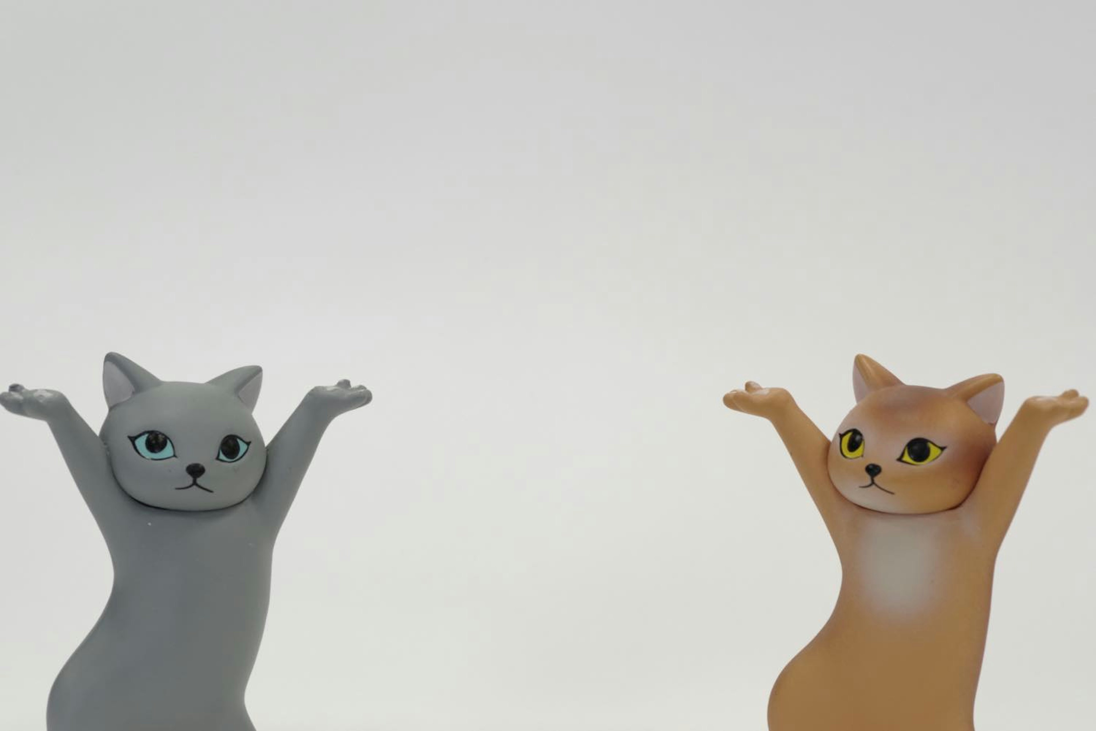 Gray and orange cat figurines raising their arms