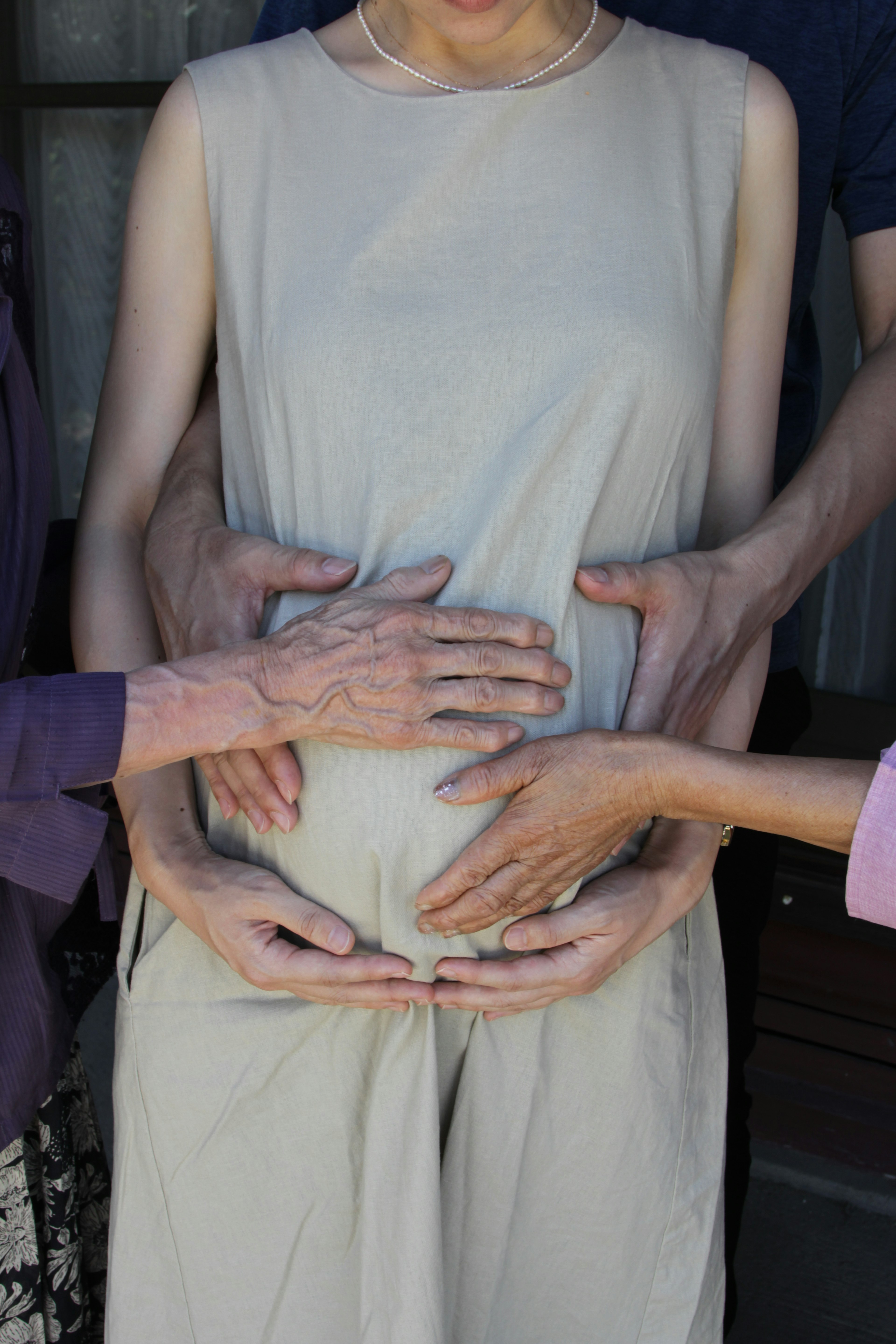 Family hands on a pregnant woman's belly