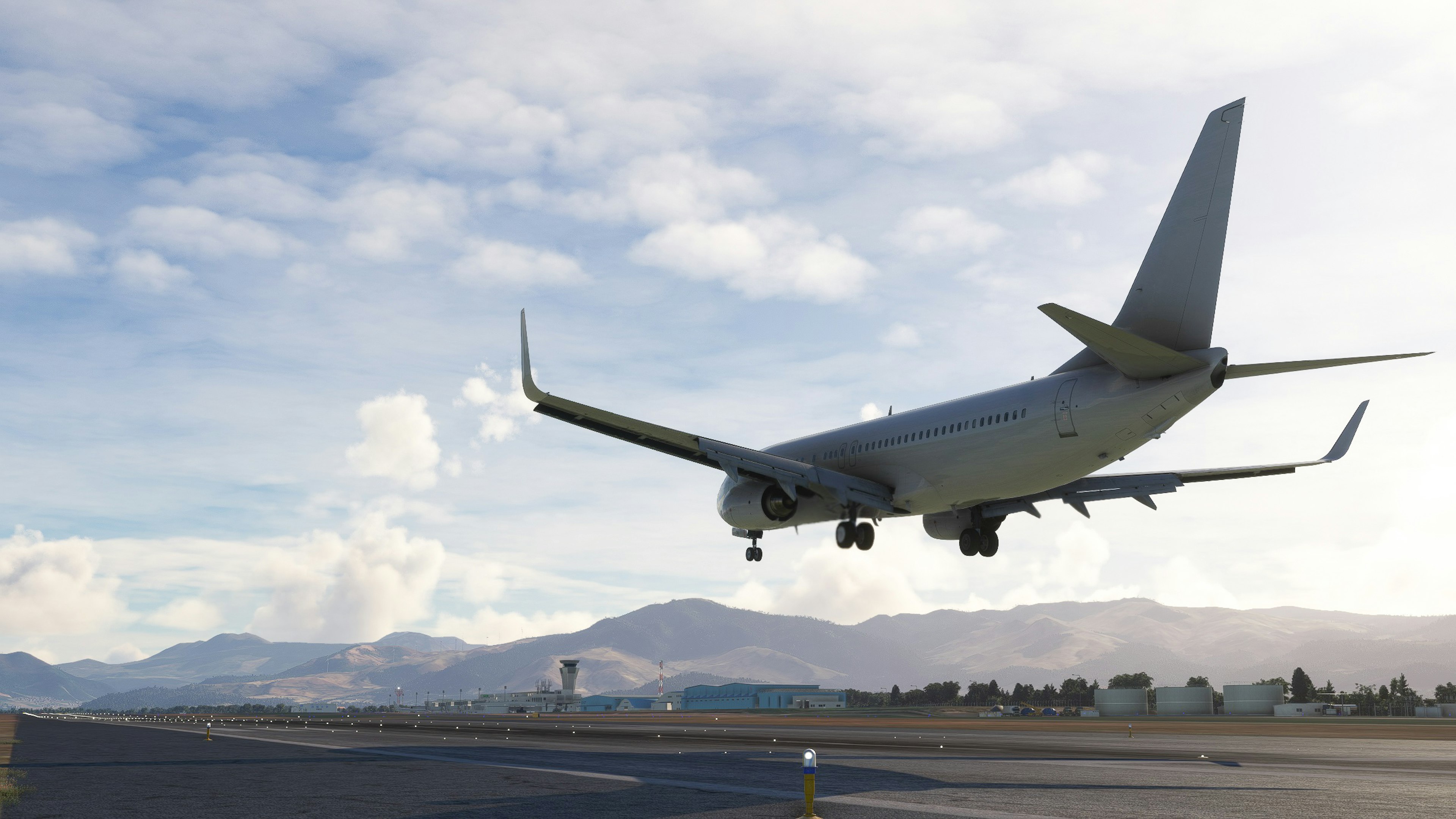 Passenger plane landing at an airport with mountains in the background