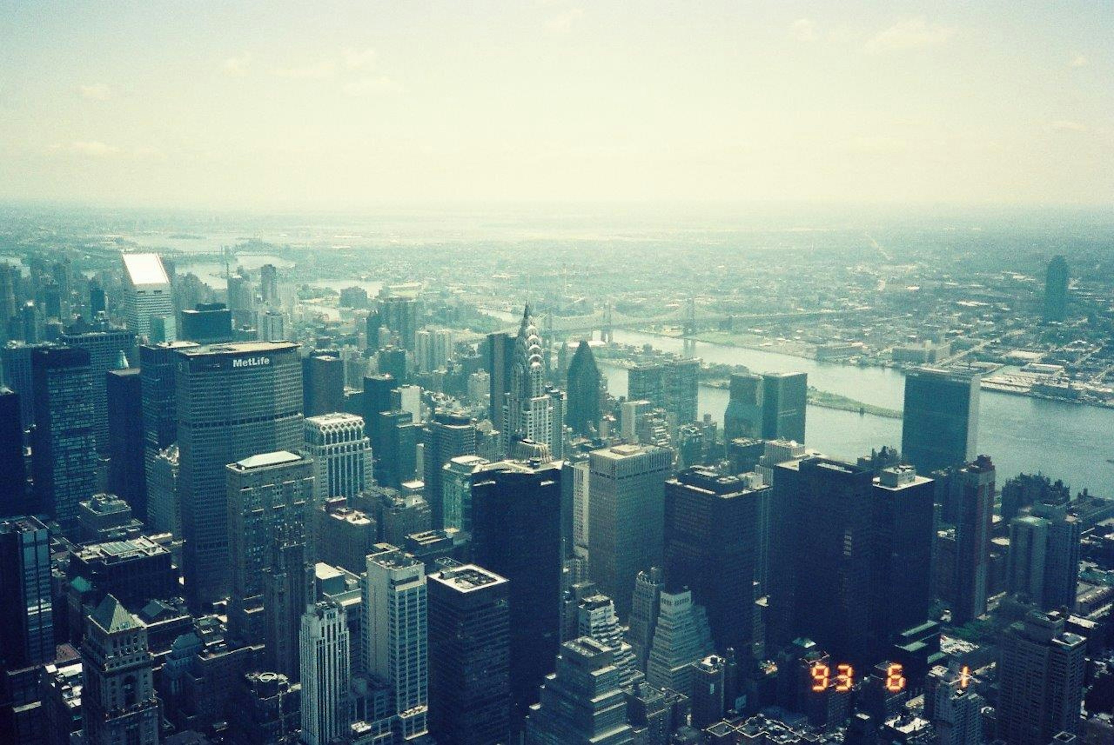 View of New York City skyline with skyscrapers and hazy sky over the river