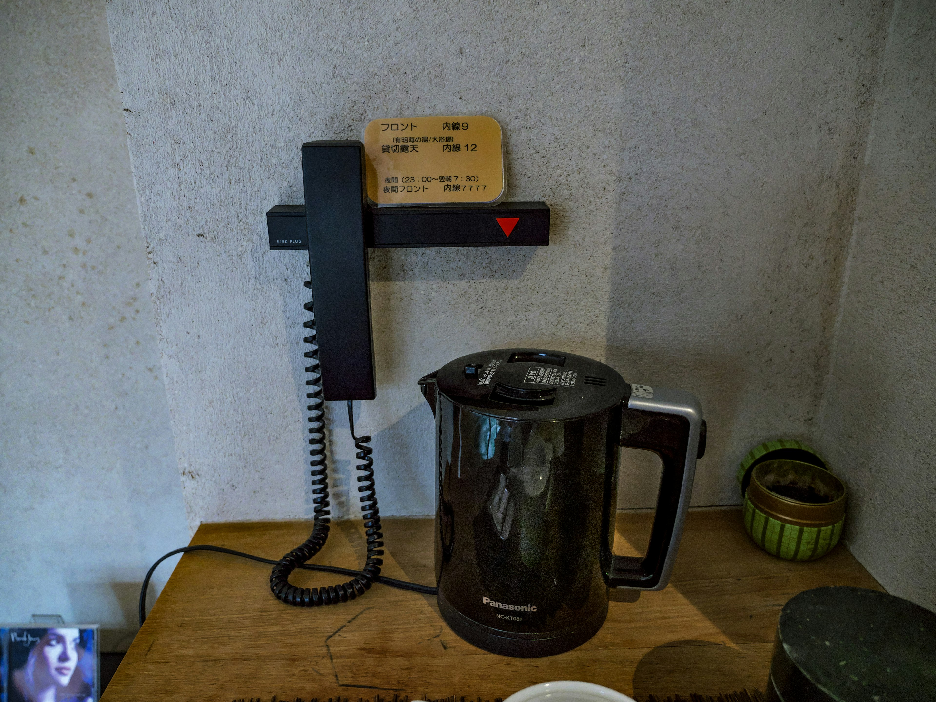 Black electric kettle and telephone on a wooden table in a cozy setting