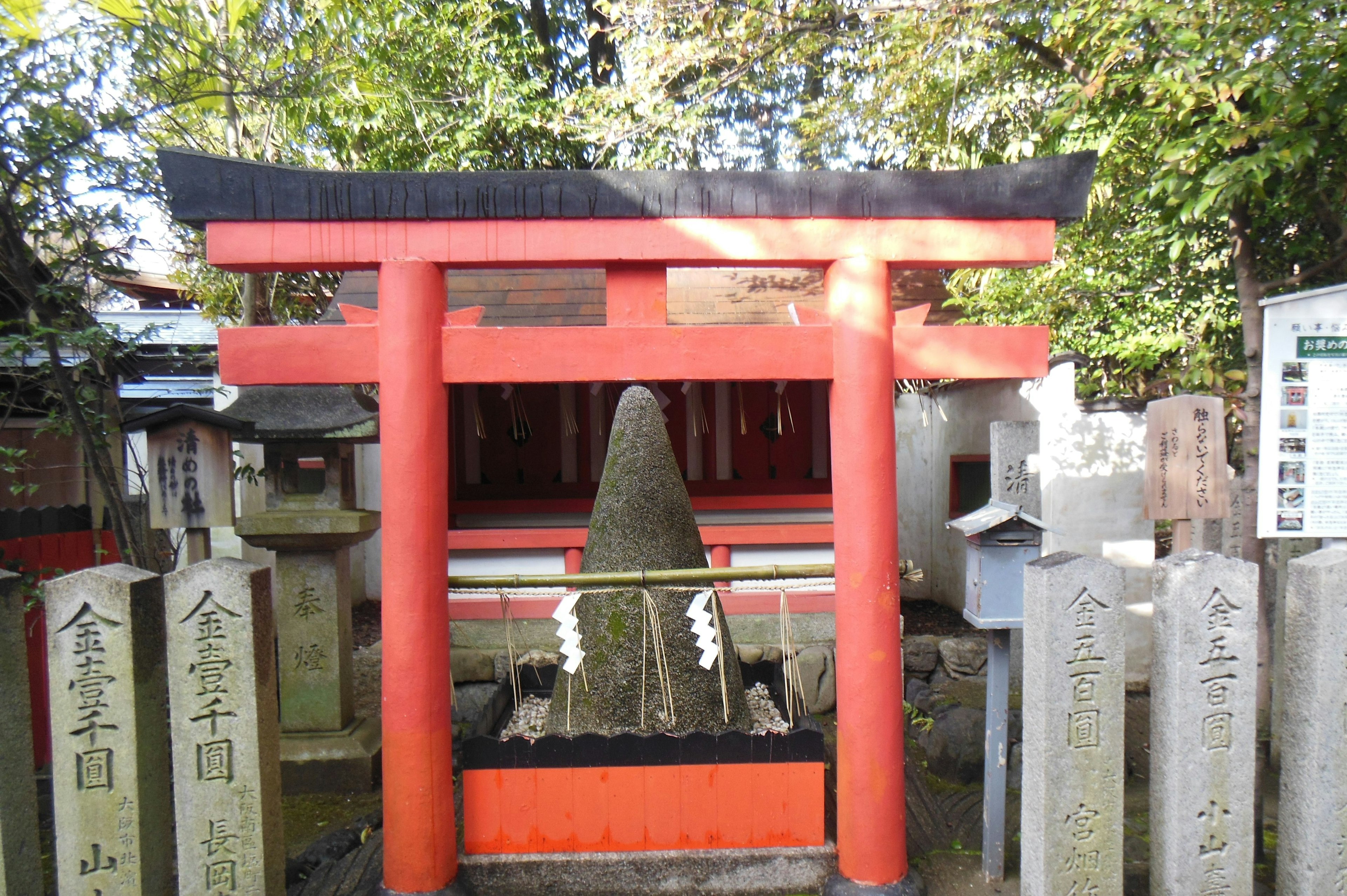 Un santuario con una puerta torii roja y monumentos de piedra