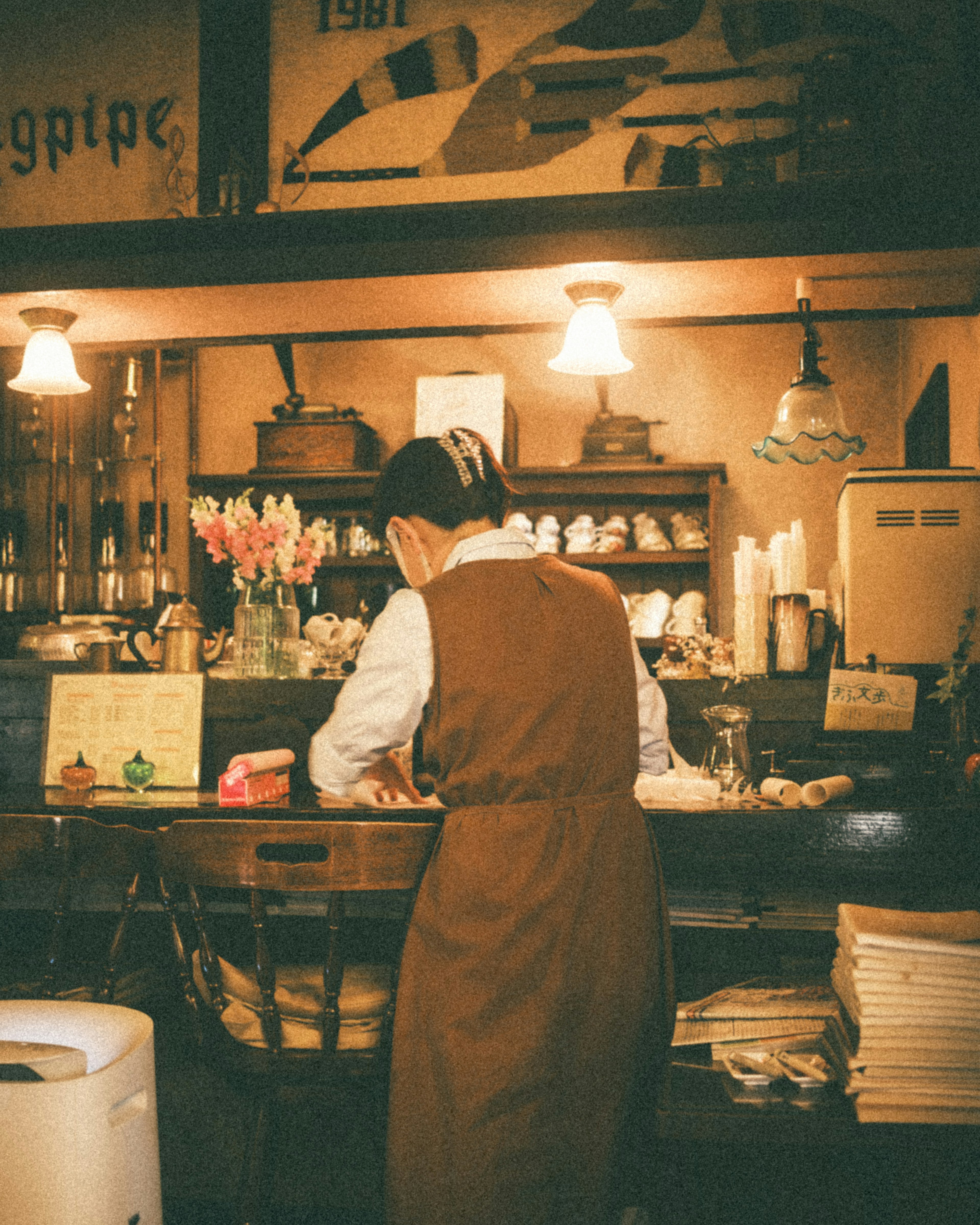 Frau arbeitet am Café-Tresen Warme Beleuchtung und Blumen im Laden