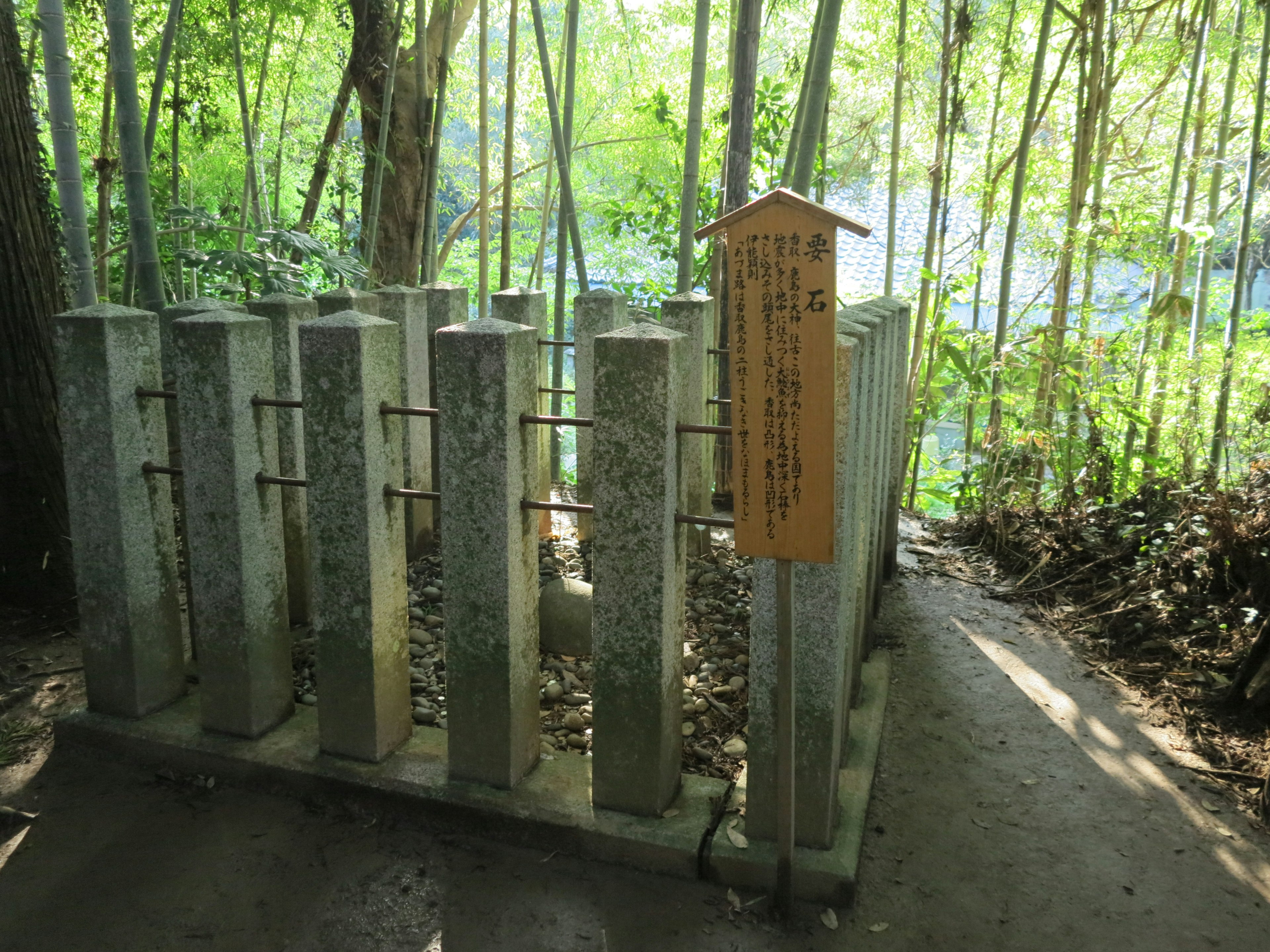 Stone structure indicating water flow in a bamboo grove with wooden sign