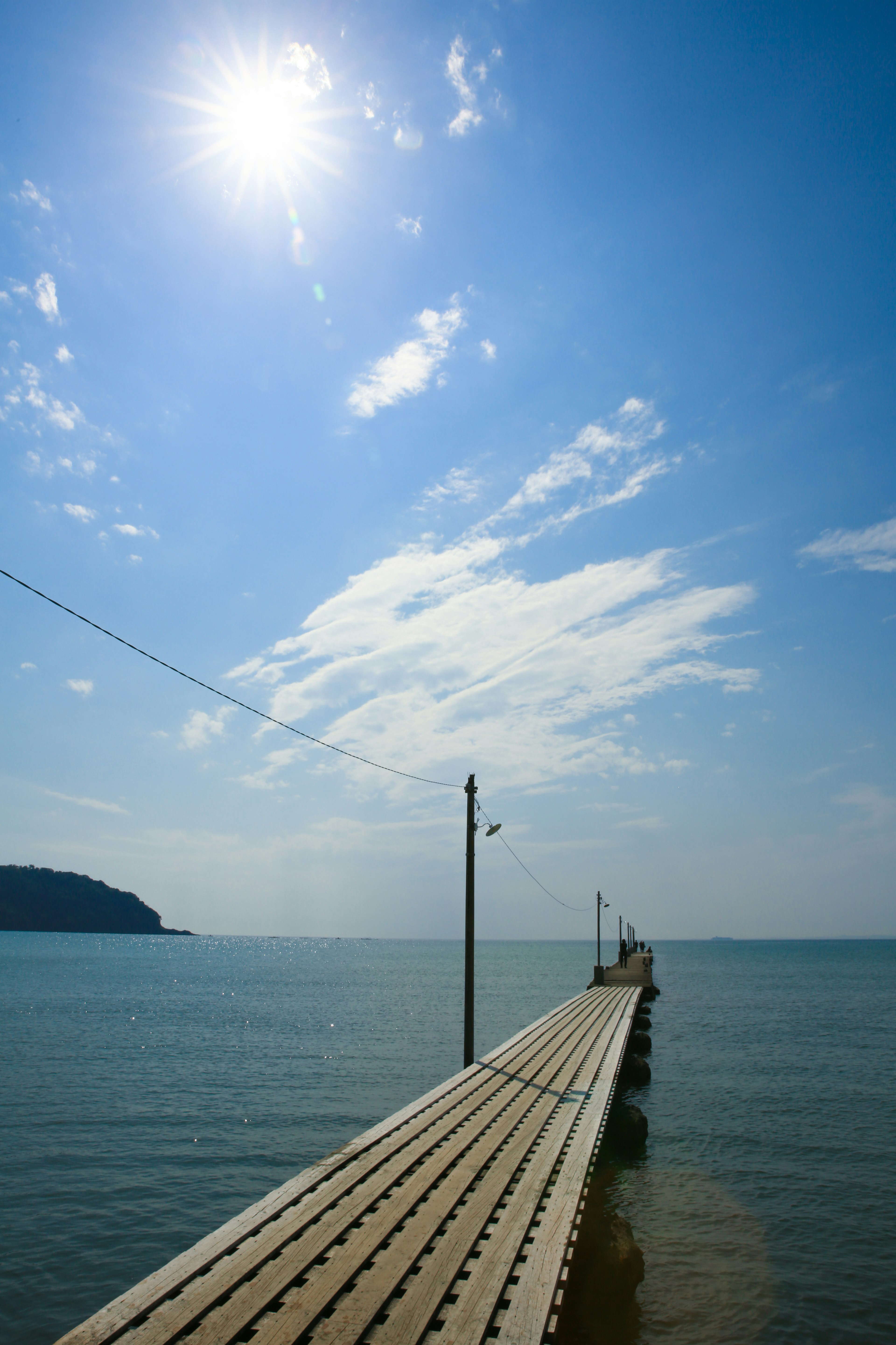 Vista escénica de un muelle que se extiende hacia el mar azul tranquilo bajo un cielo brillante