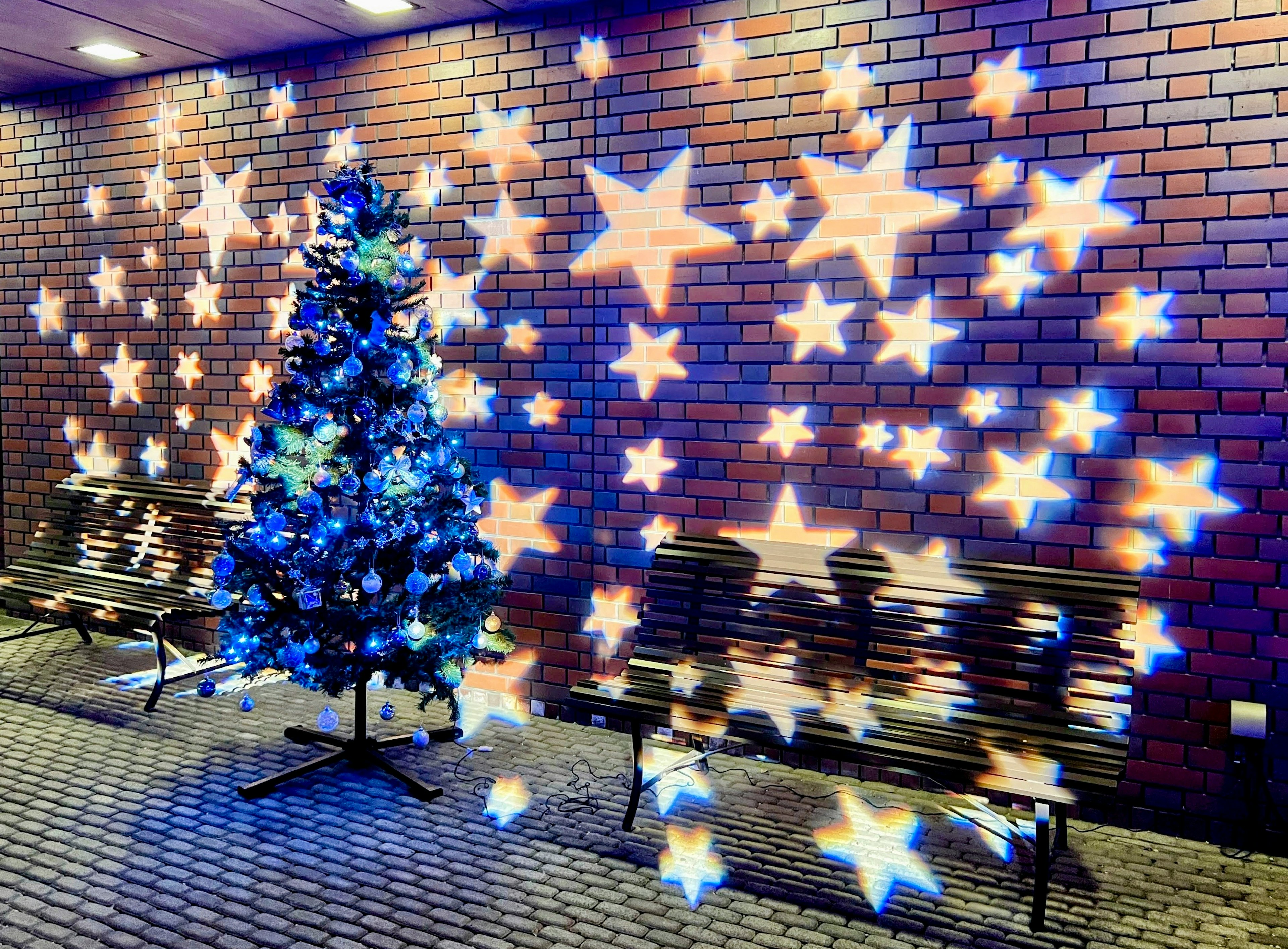 Arbre de Noël bleu avec des décorations en étoiles sur un mur en briques