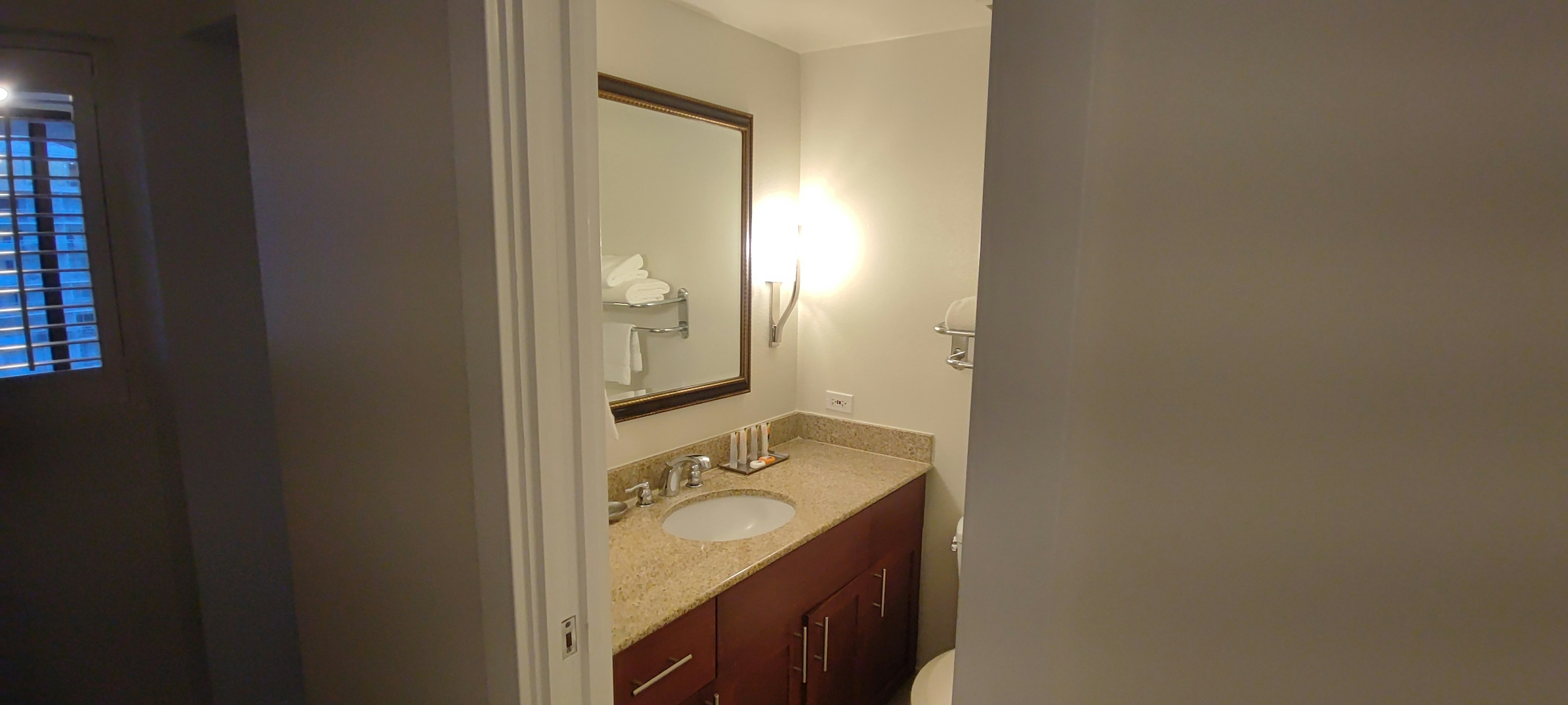 Vue intérieure d'une salle de bain avec des murs de couleur claire, un lavabo, un miroir et des cabinets en bois