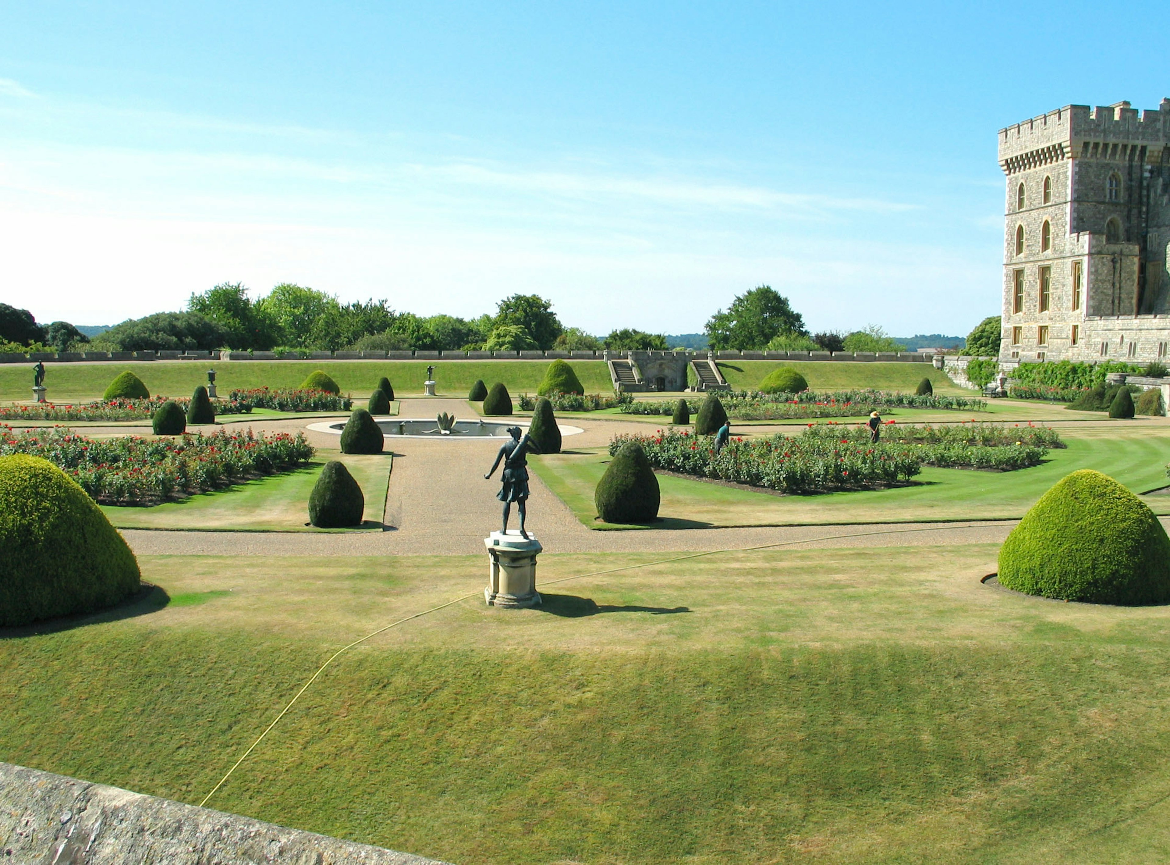 Vue pittoresque d'un jardin avec pelouses soignées et un château en arrière-plan