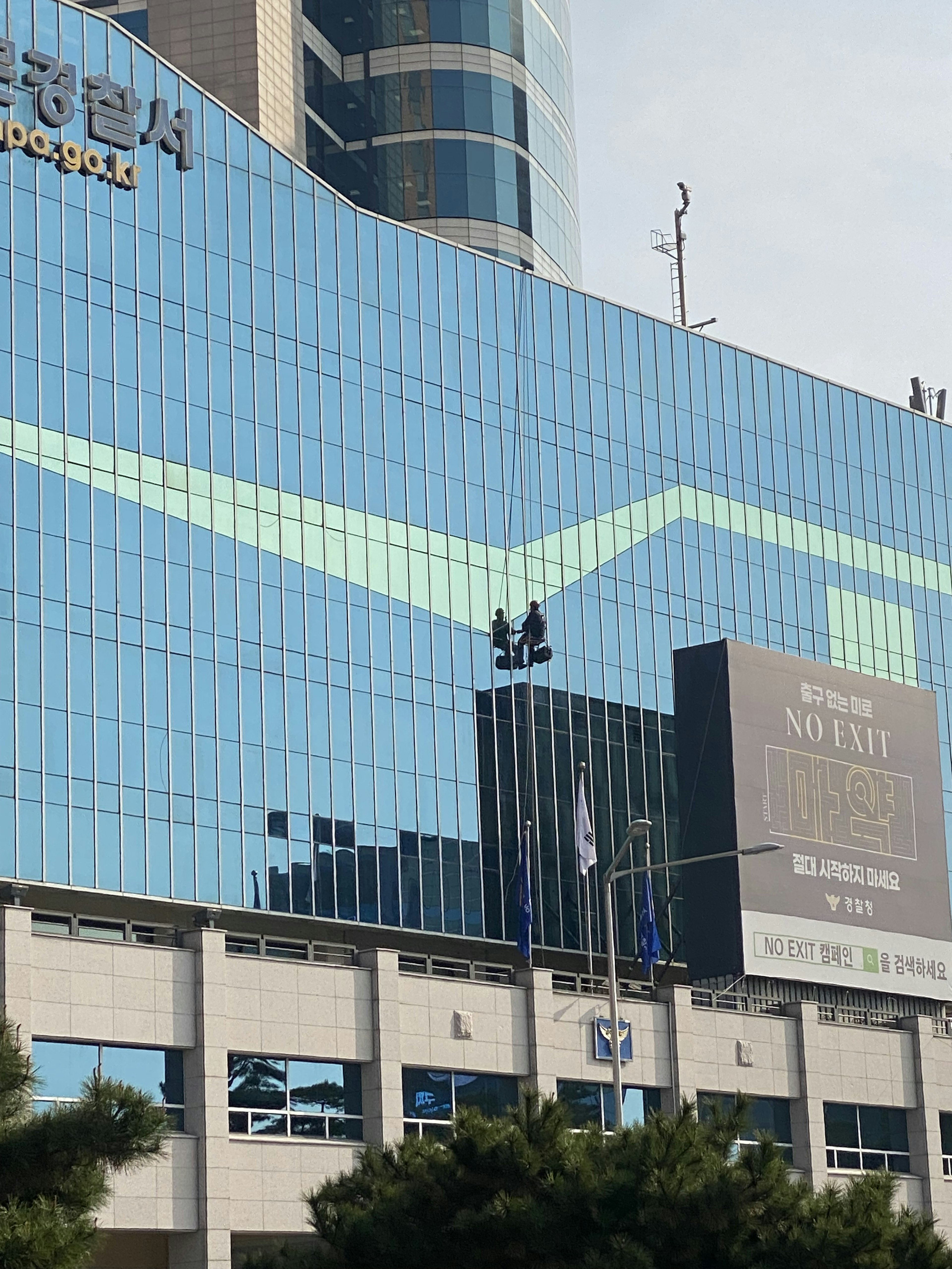 High-rise building with a blue glass facade displaying advertisements