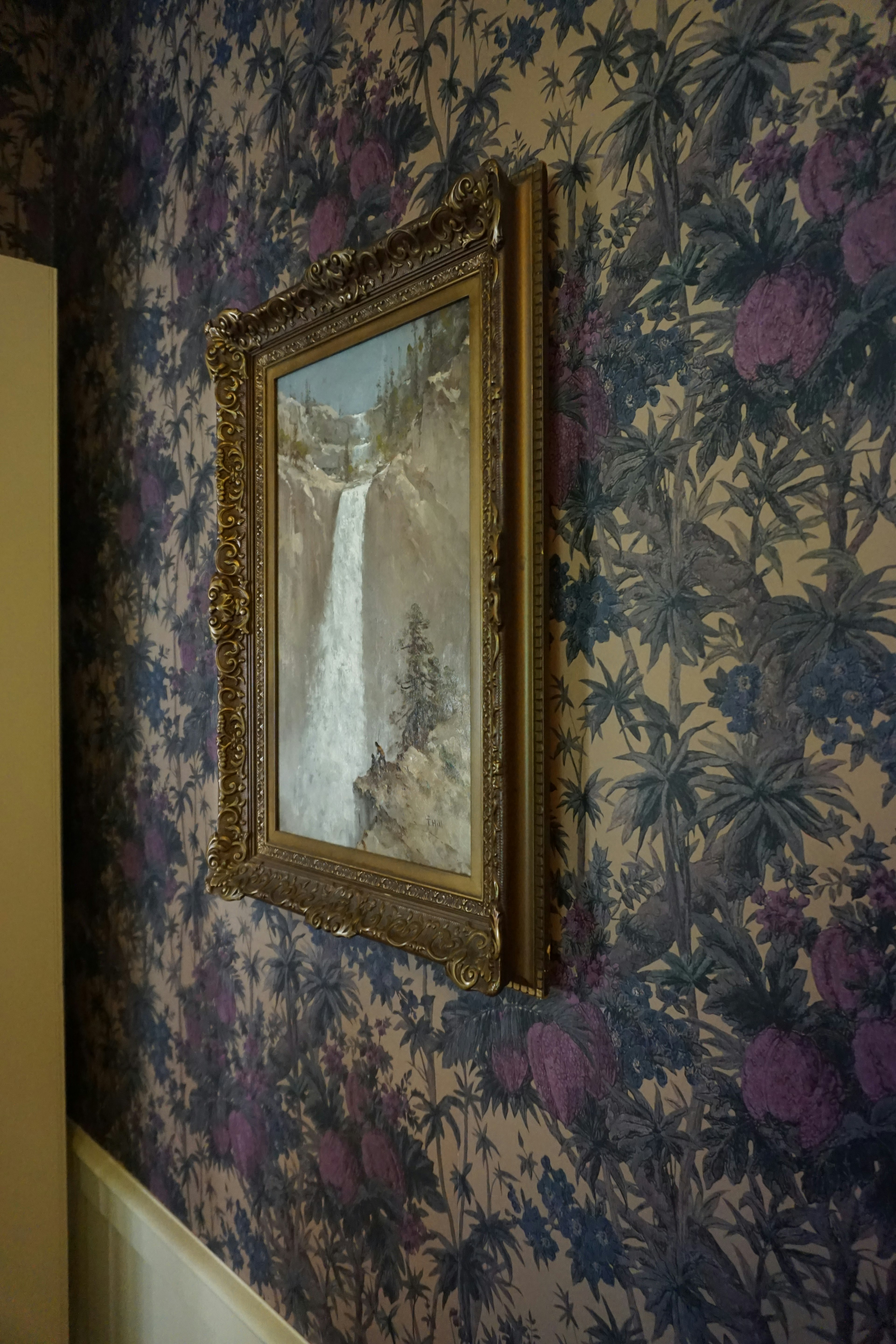 Landscape painting framed on a floral wallpaper