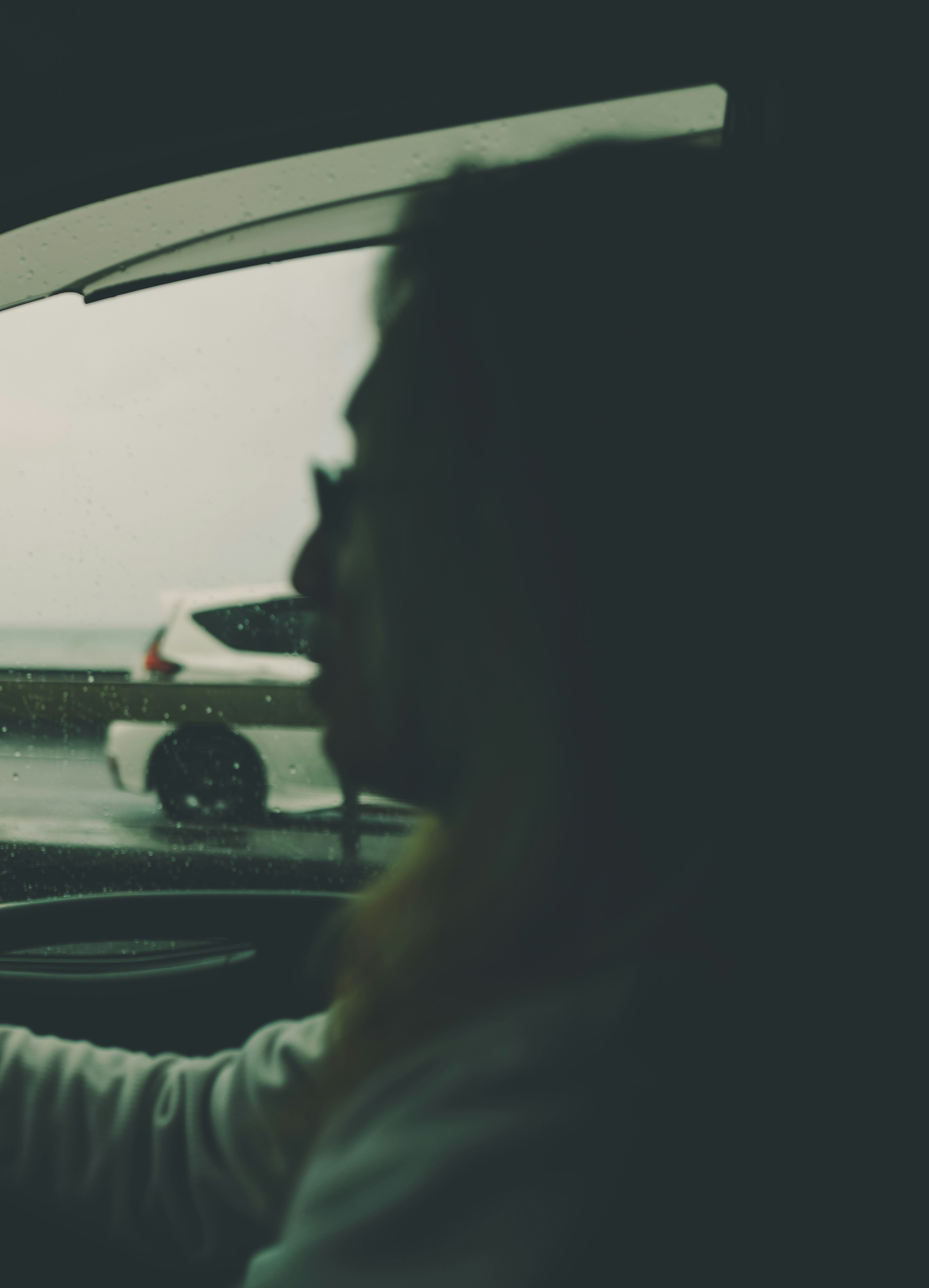 Silhouette of a person driving with a rainy background