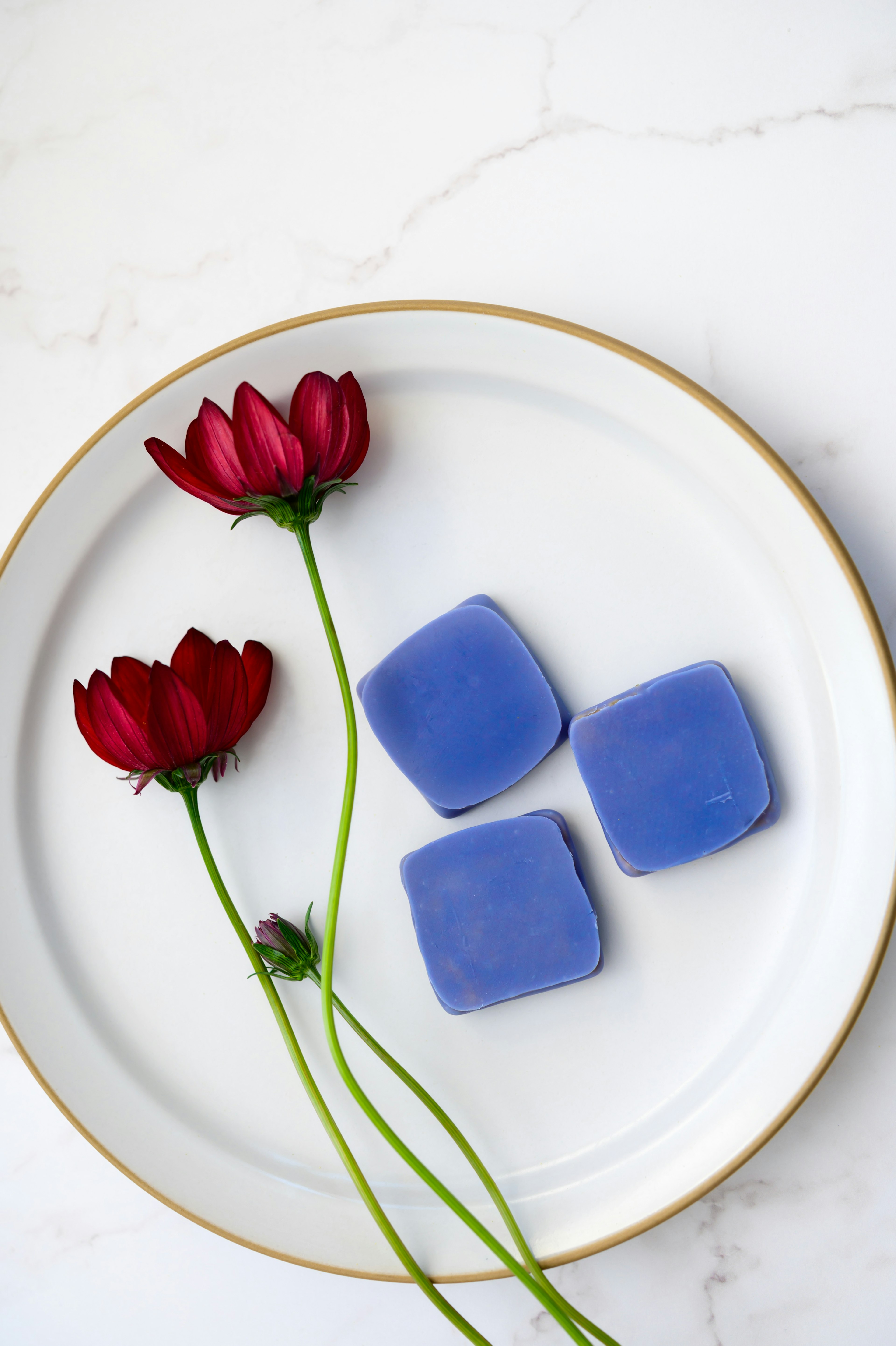 Purple square candies arranged with red flowers on a white plate