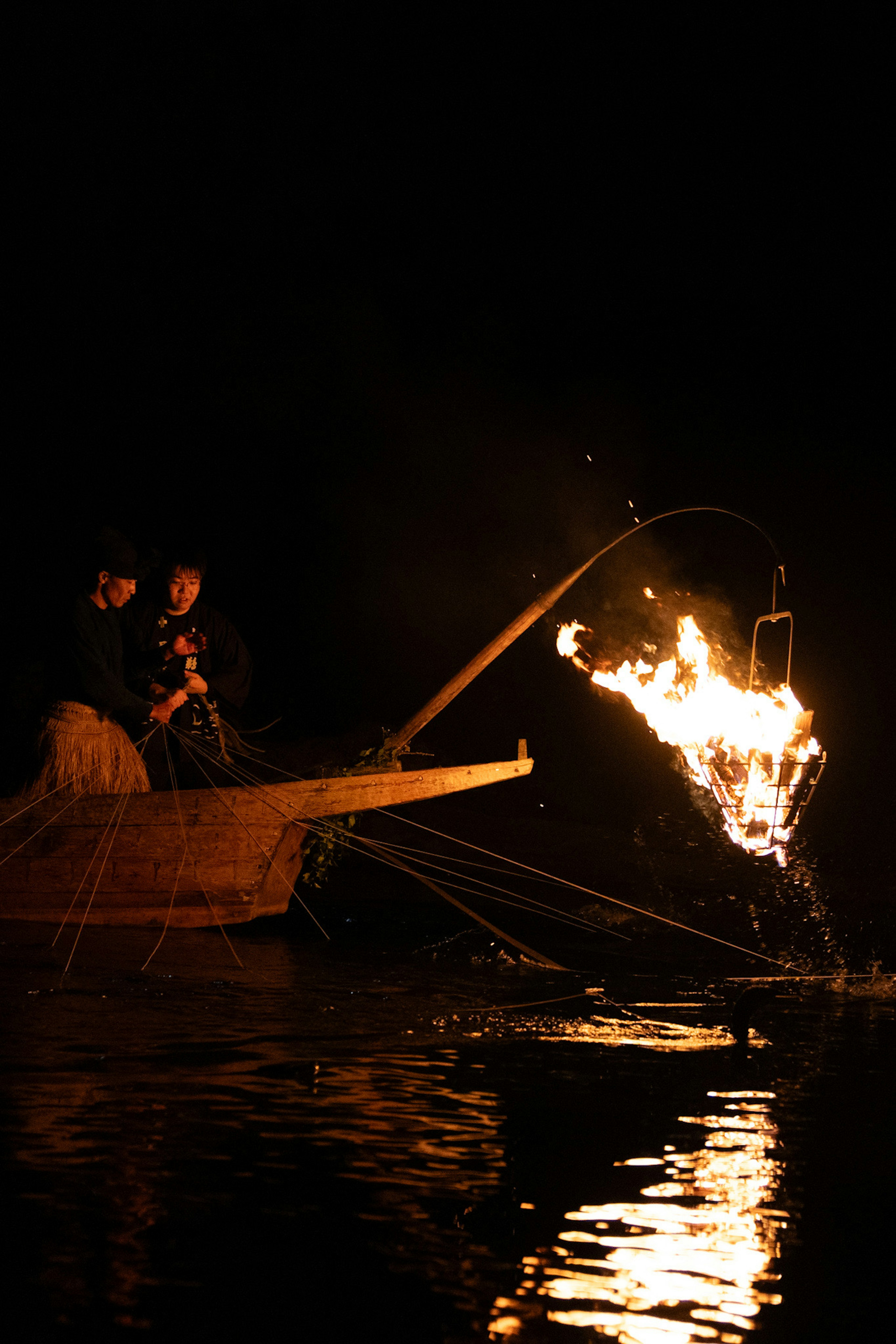 Des pêcheurs utilisant le feu pour pêcher sur une rivière la nuit