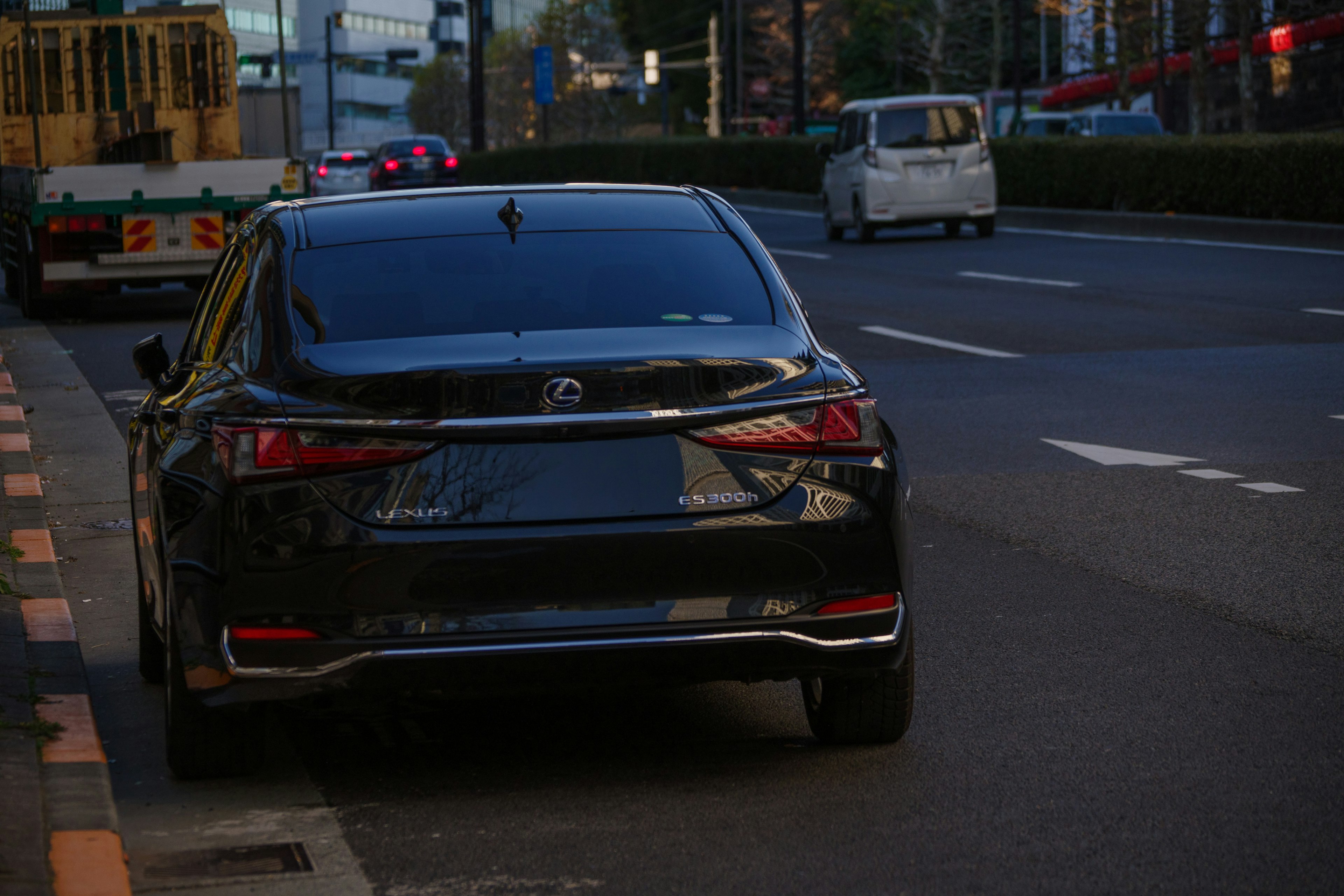 A black car parked beside the road with a cityscape in the background