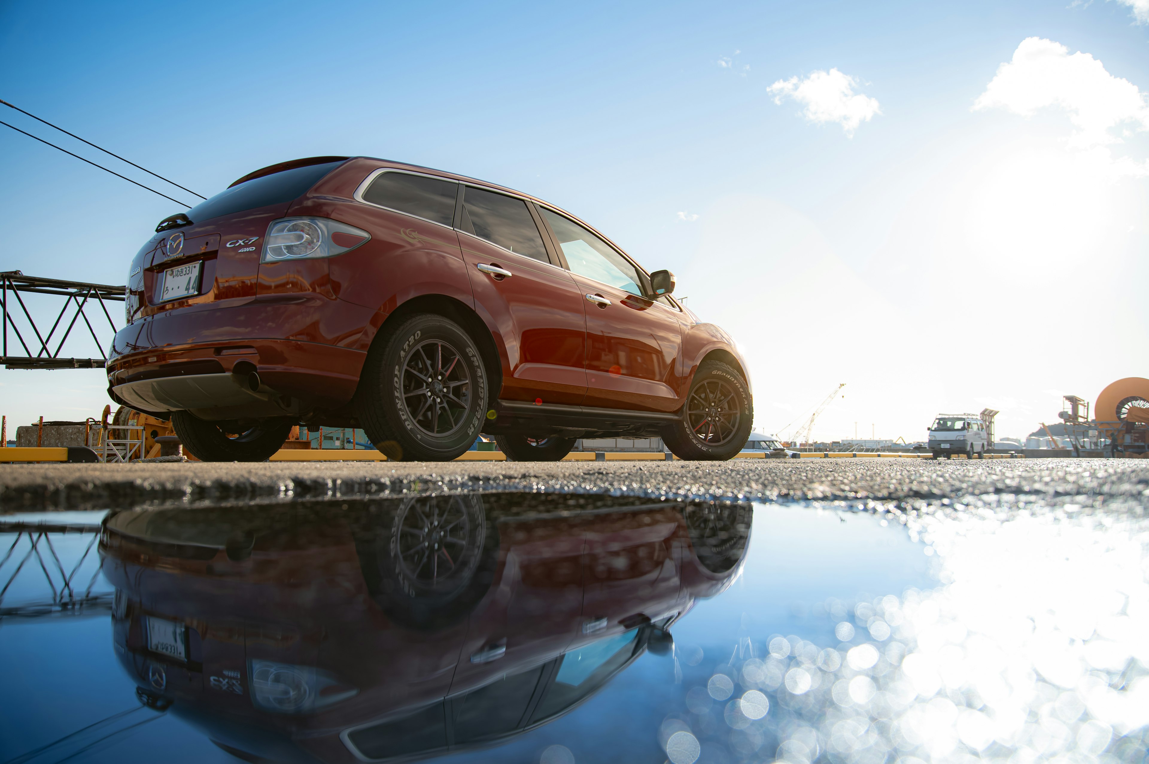 Roter SUV, der neben einer Pfütze steht und den Himmel reflektiert