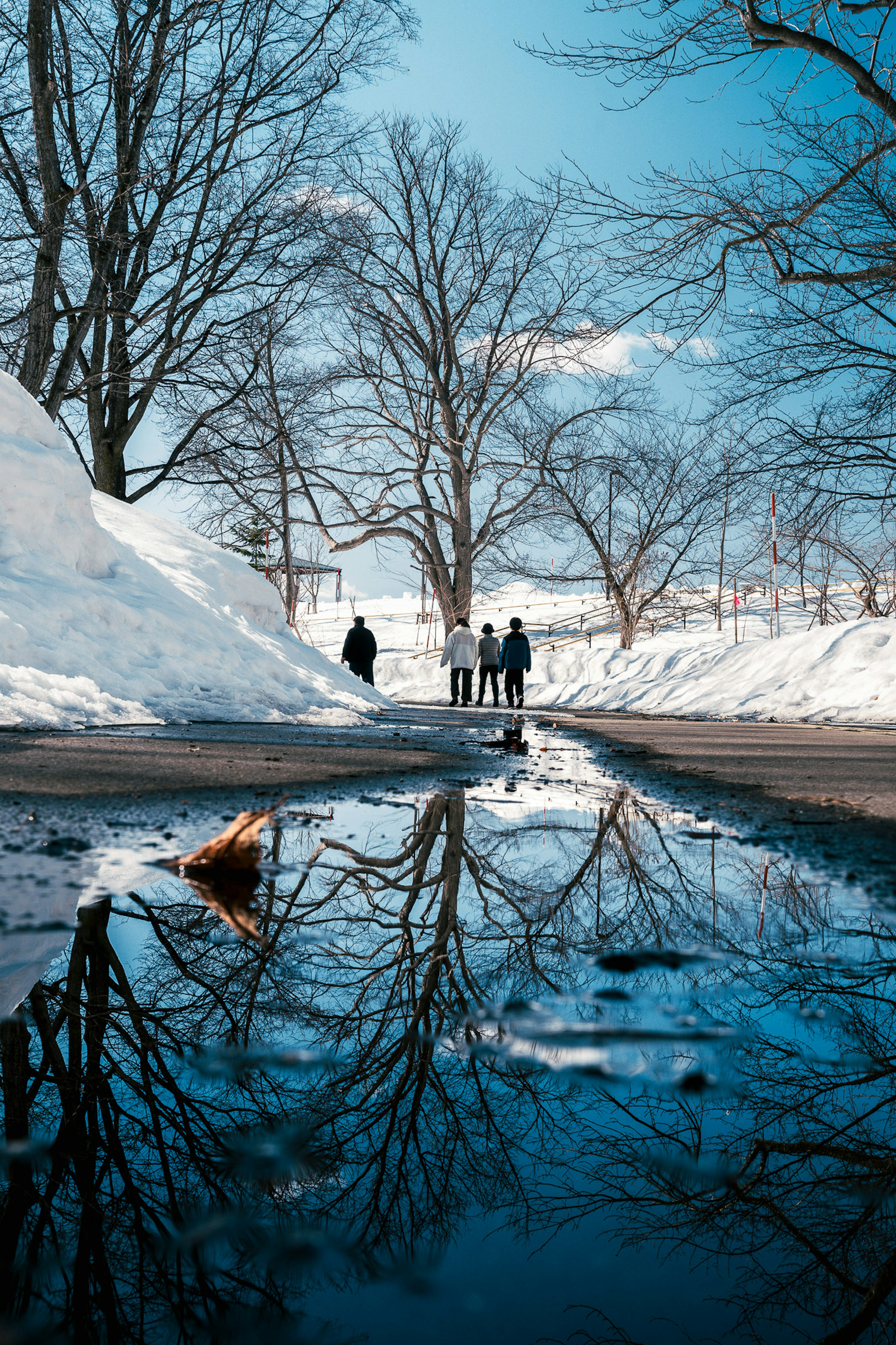 Winterszene mit Menschen, die im Schnee gehen und ihrem Spiegelbild im Wasser