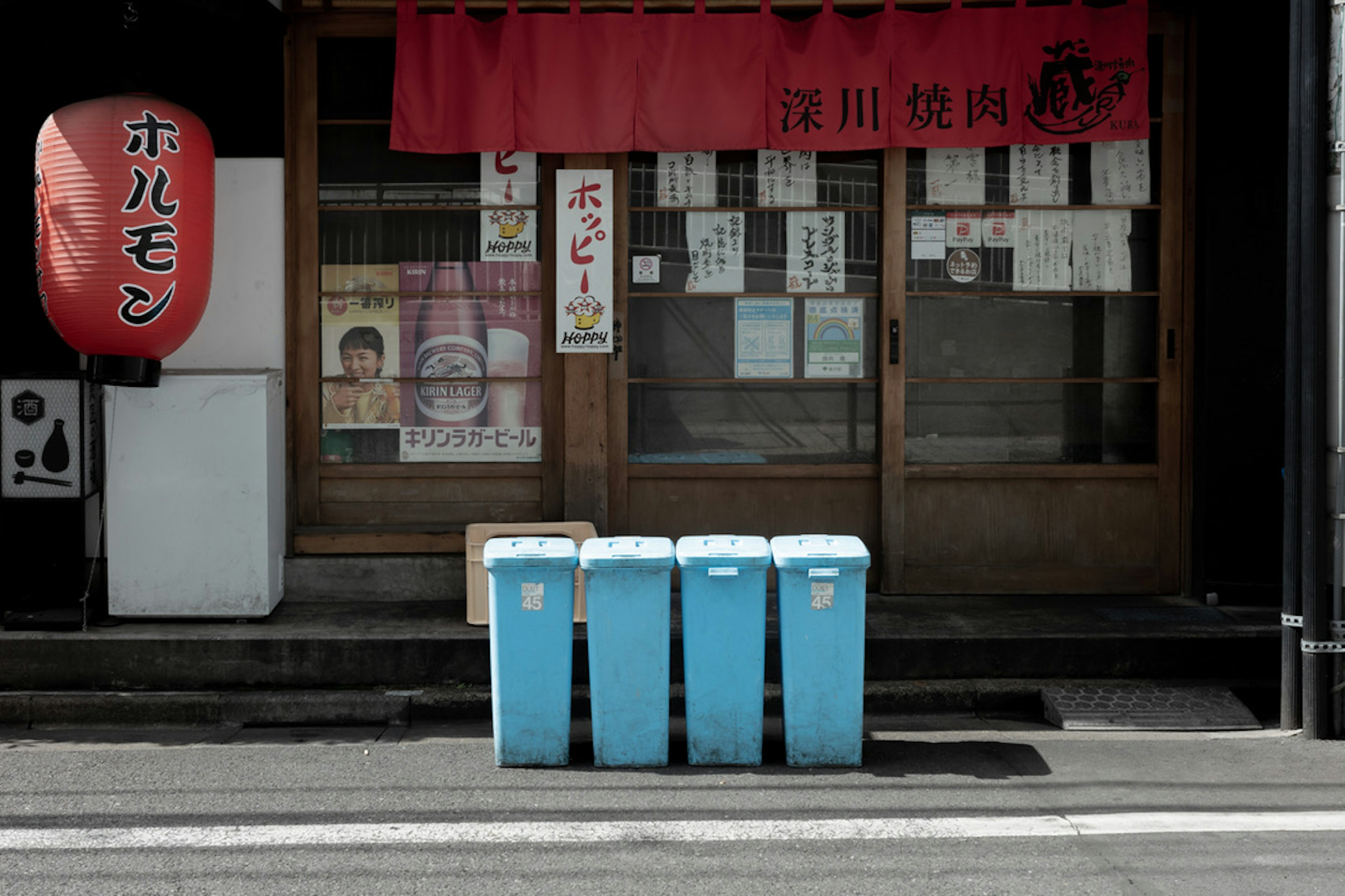 青いゴミ箱が並ぶ日本の店舗の前景