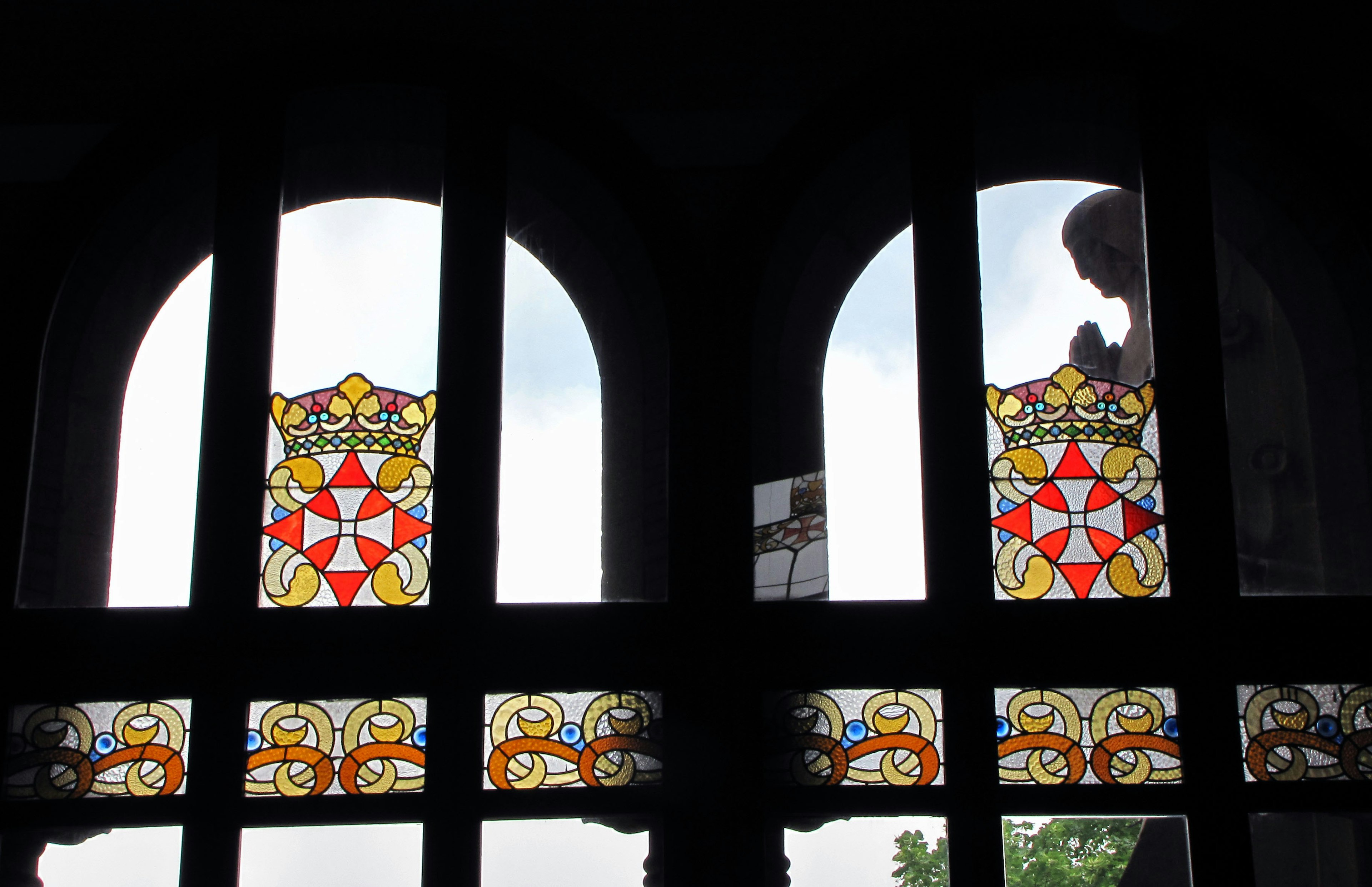 Silhouette einer betenden Person hinter schönen Buntglasfenstern