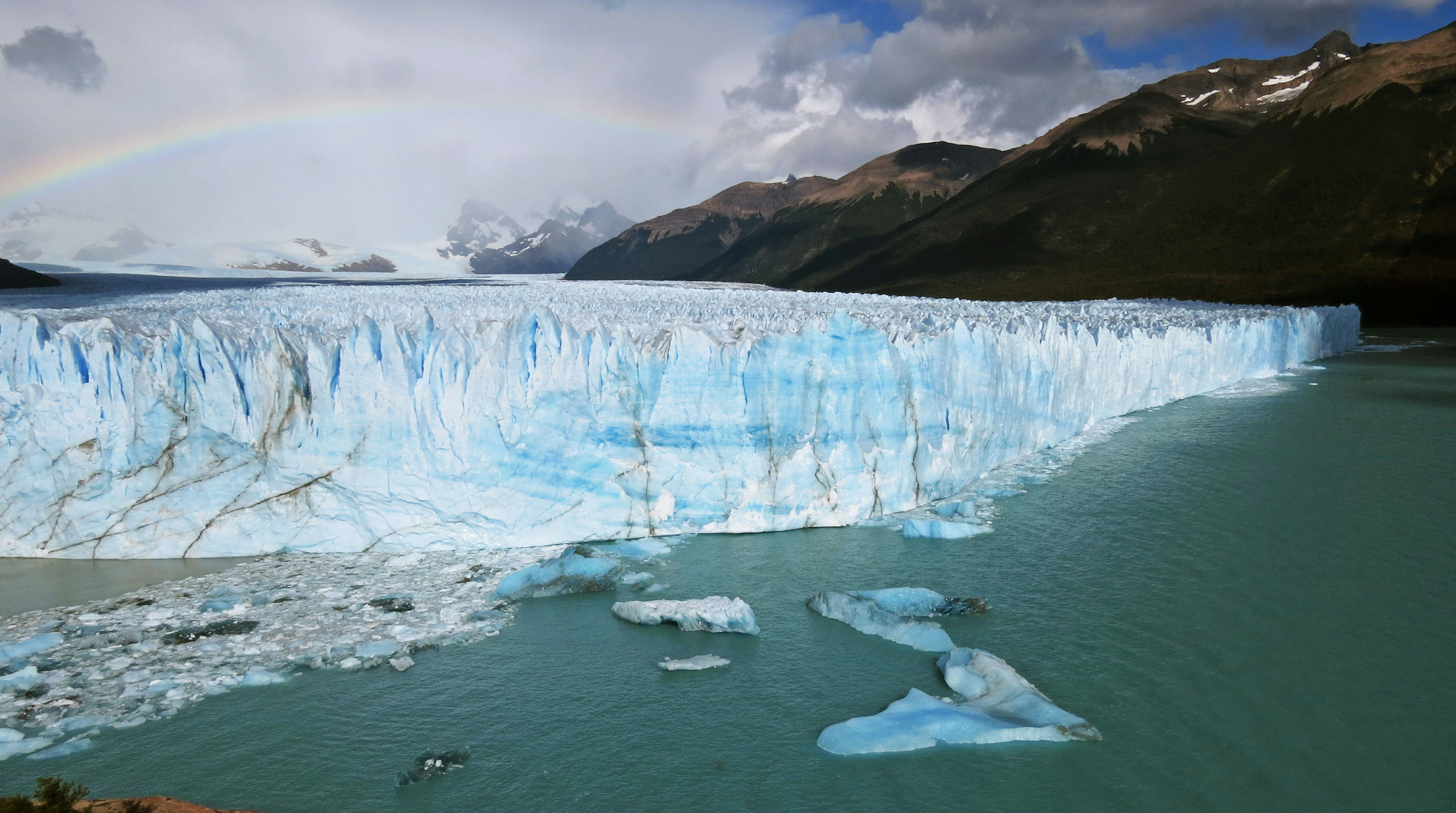 Impresionante vista del glaciar y el lago con un arcoíris