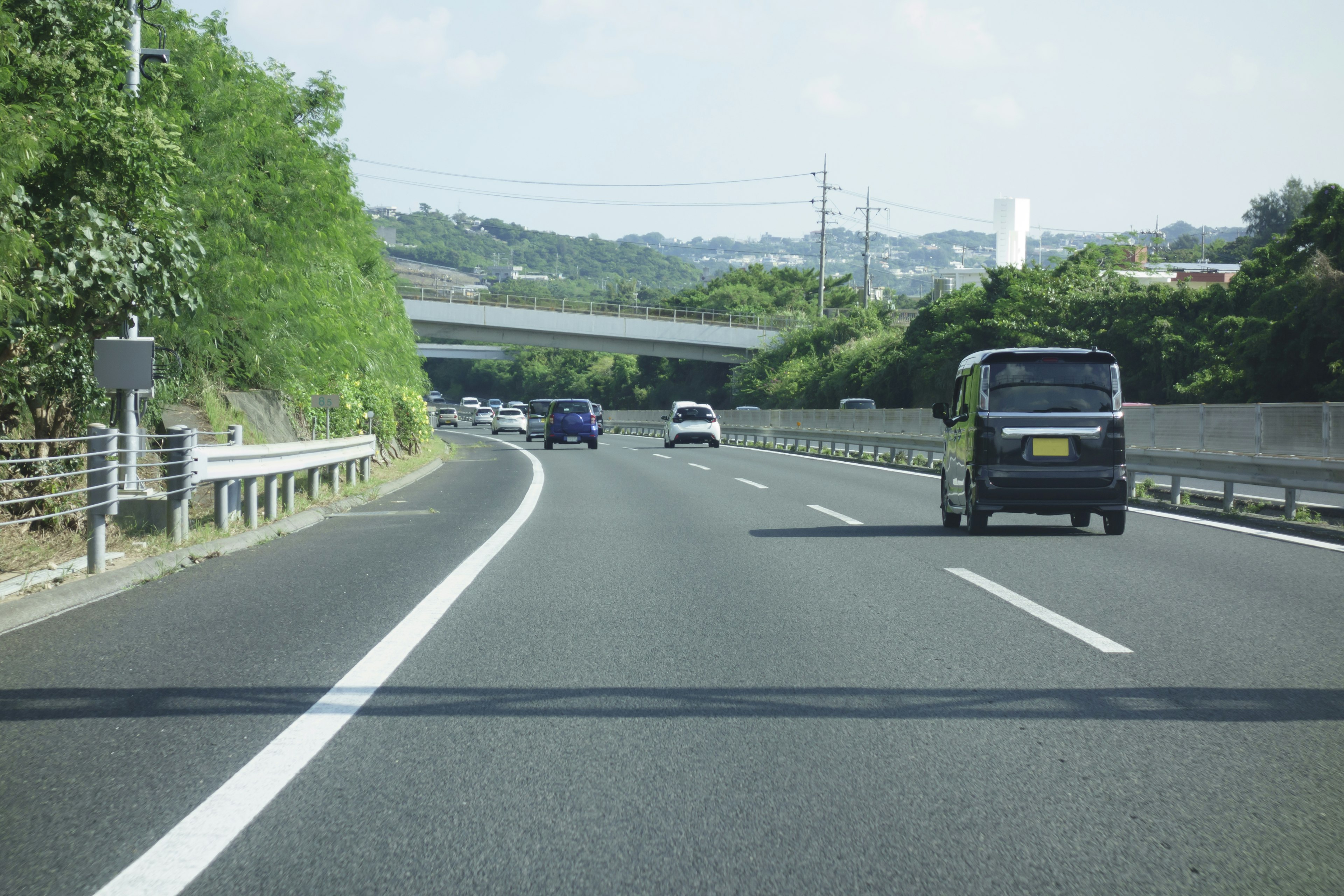 Vista escénica de una carretera rodeada de árboles verdes con vehículos en movimiento