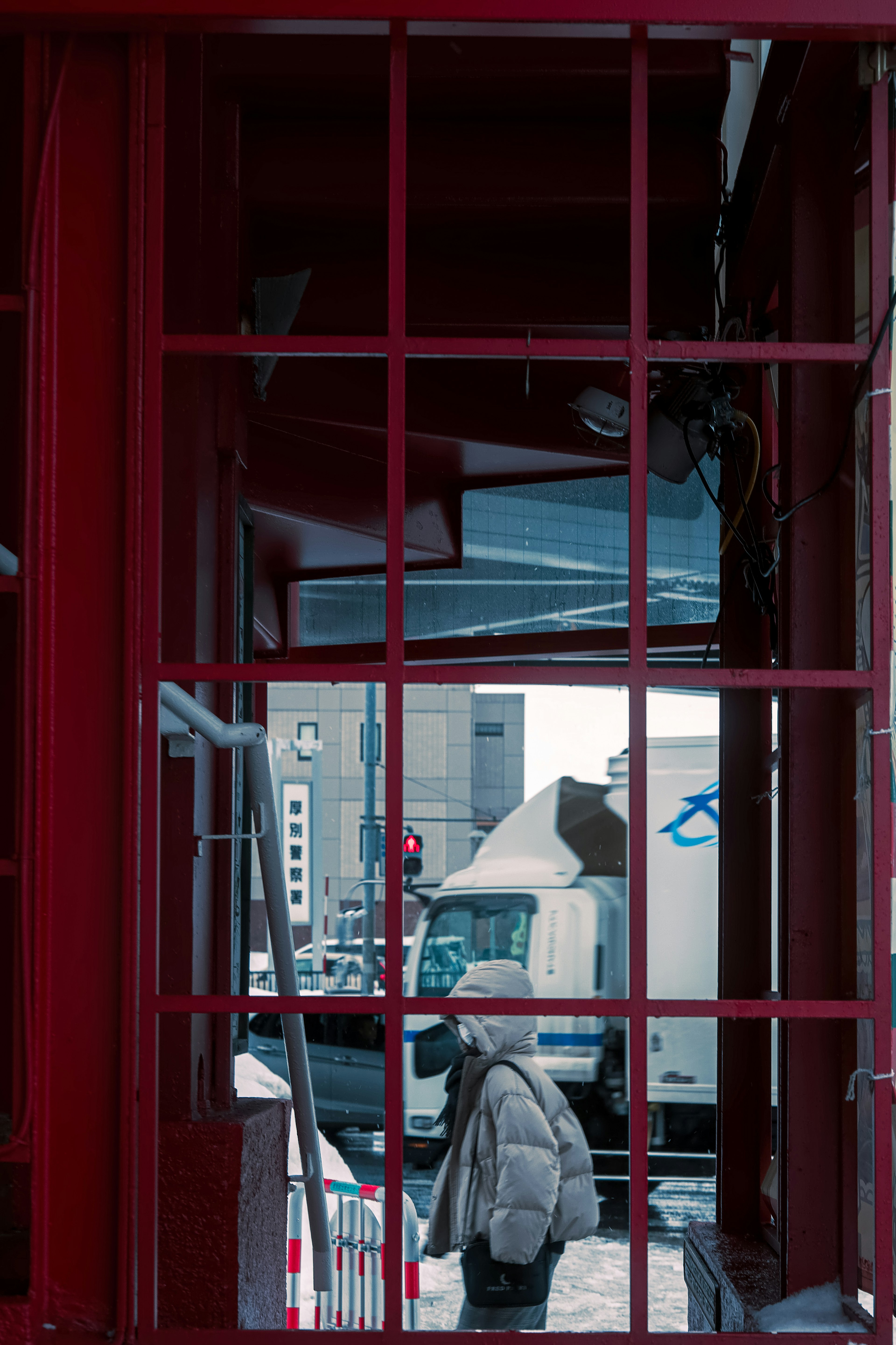 View of a cityscape and a person through the window of a red telephone booth