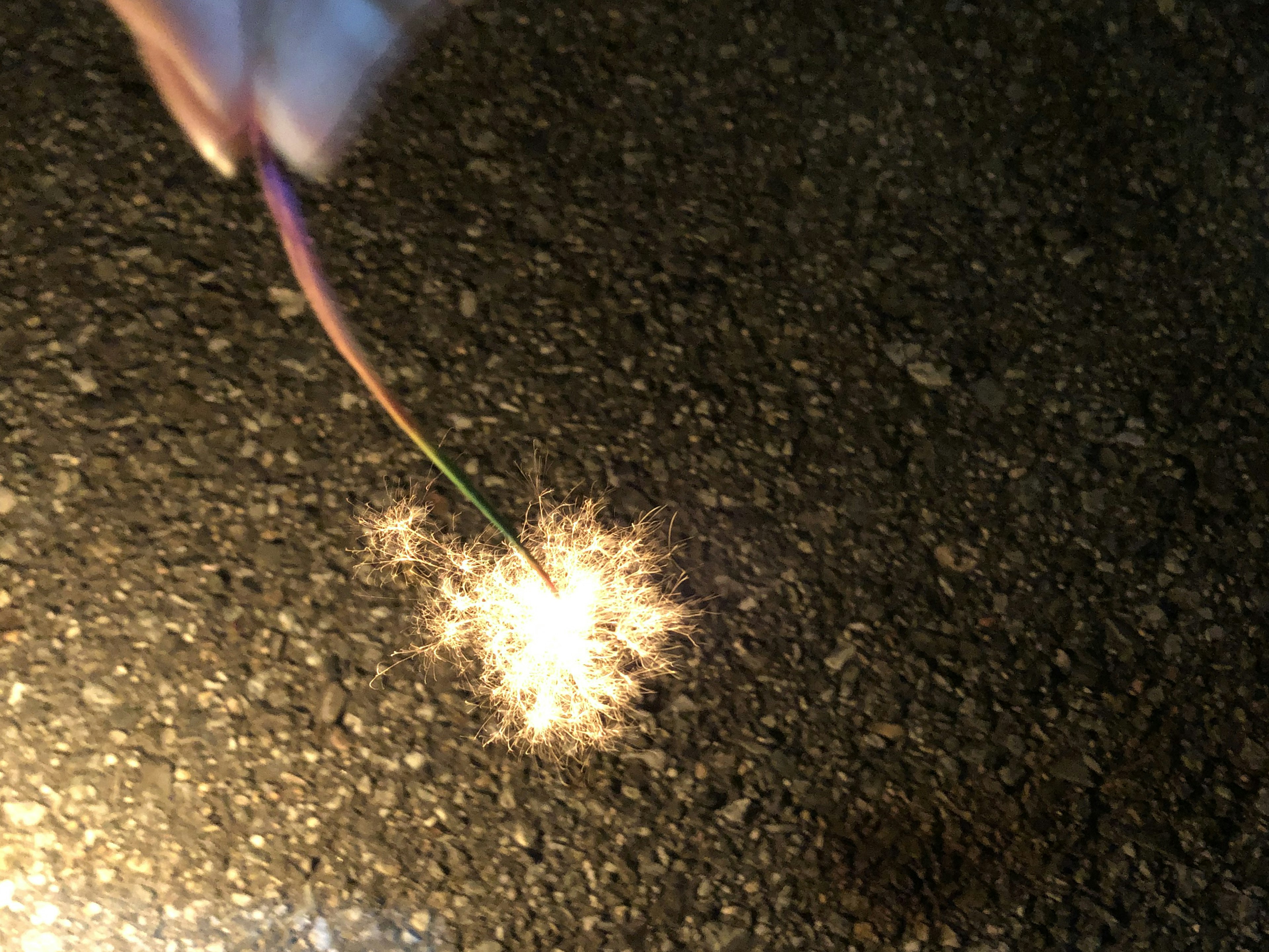 Una mano che tiene un fuoco d'artificio che emette scintille luminose