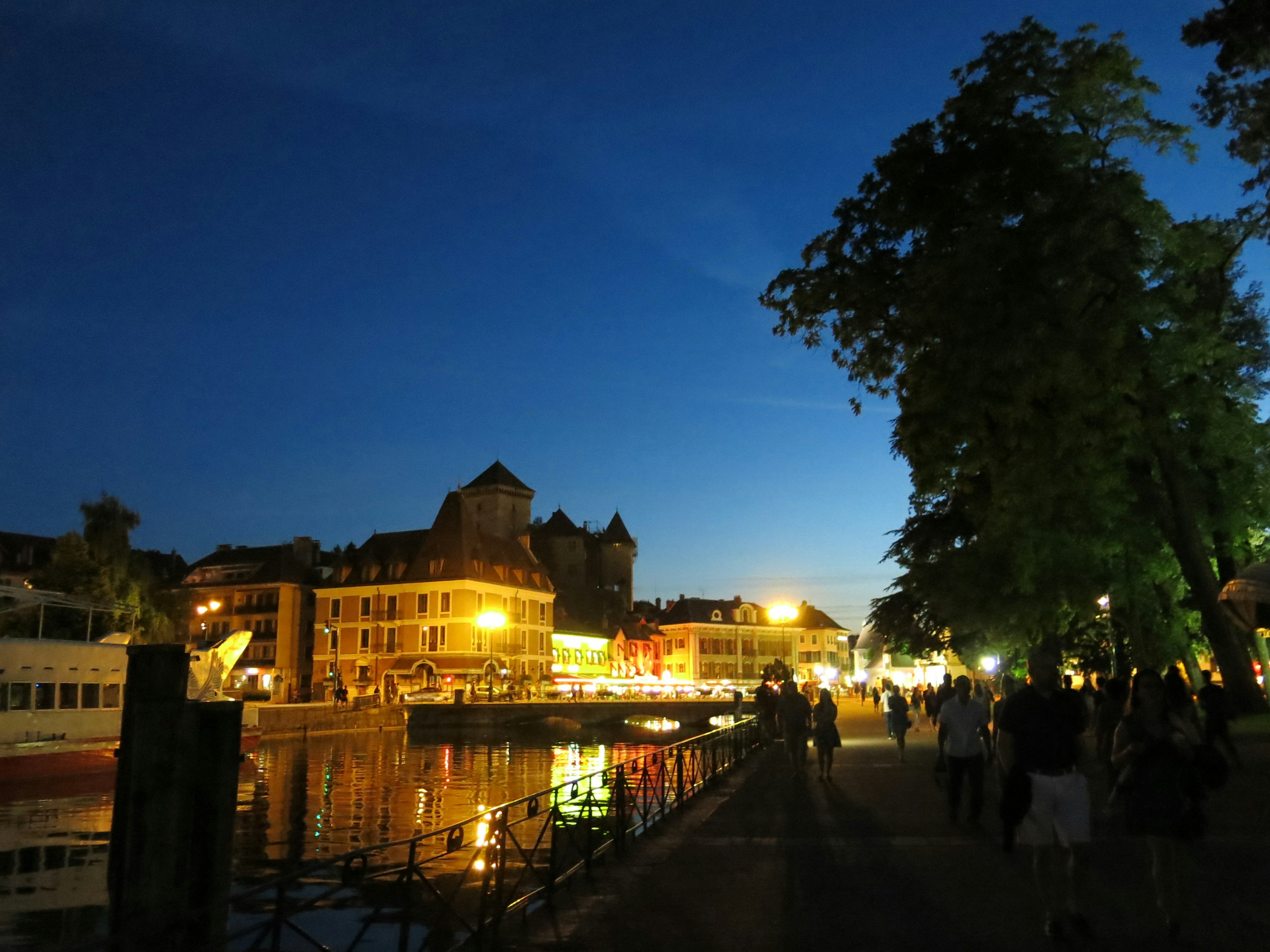 Nighttime riverside cityscape with people strolling