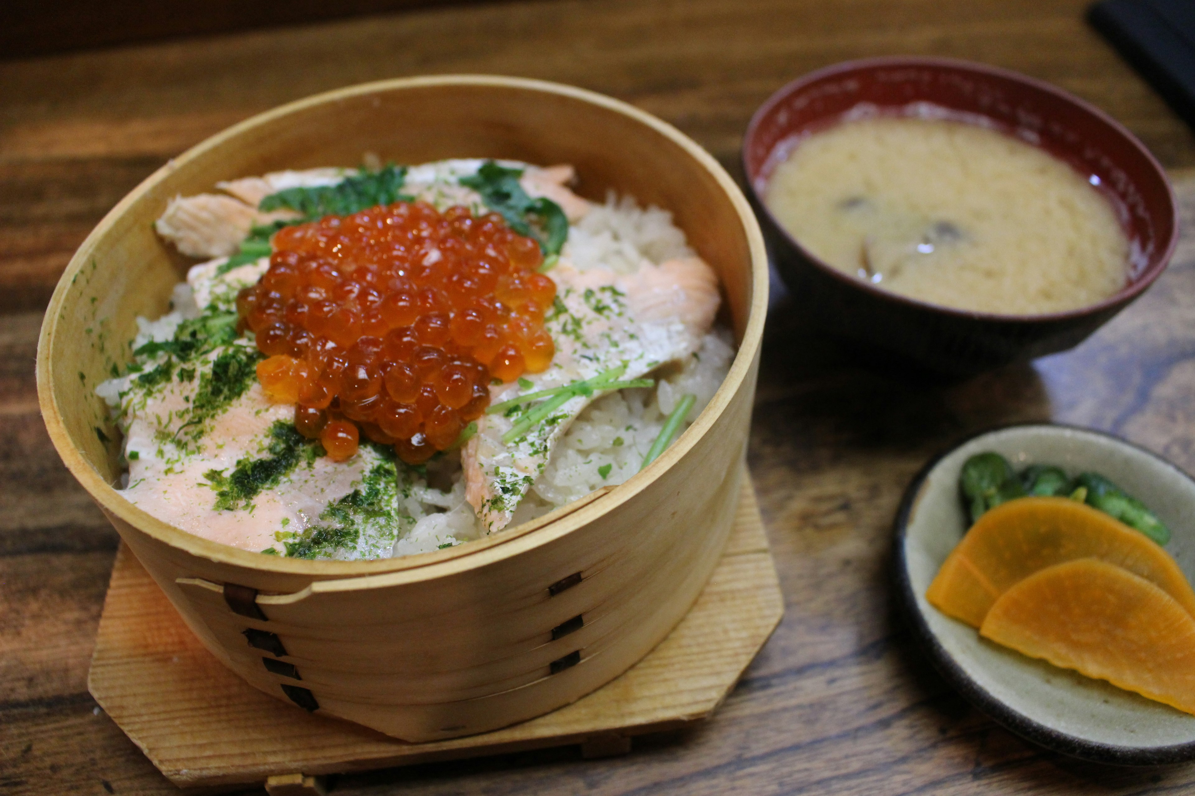 Hidangan nasi dengan salmon dan ikura dalam mangkuk kayu