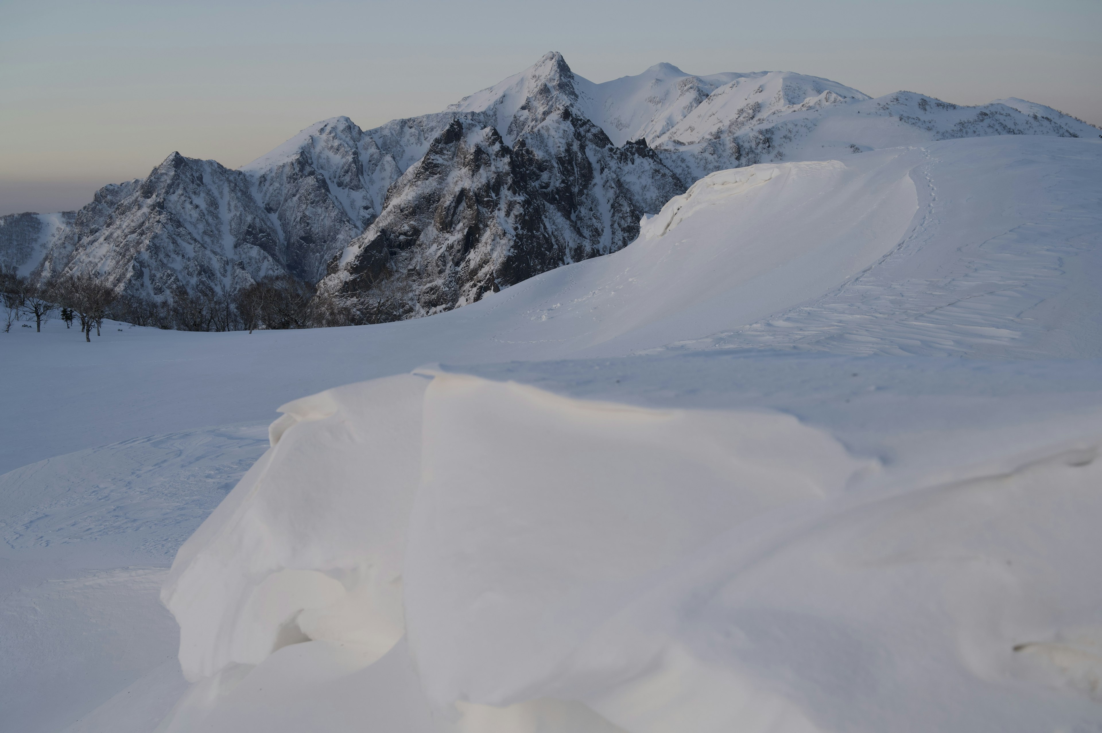 Paisaje montañoso cubierto de nieve con colinas de nieve blanca