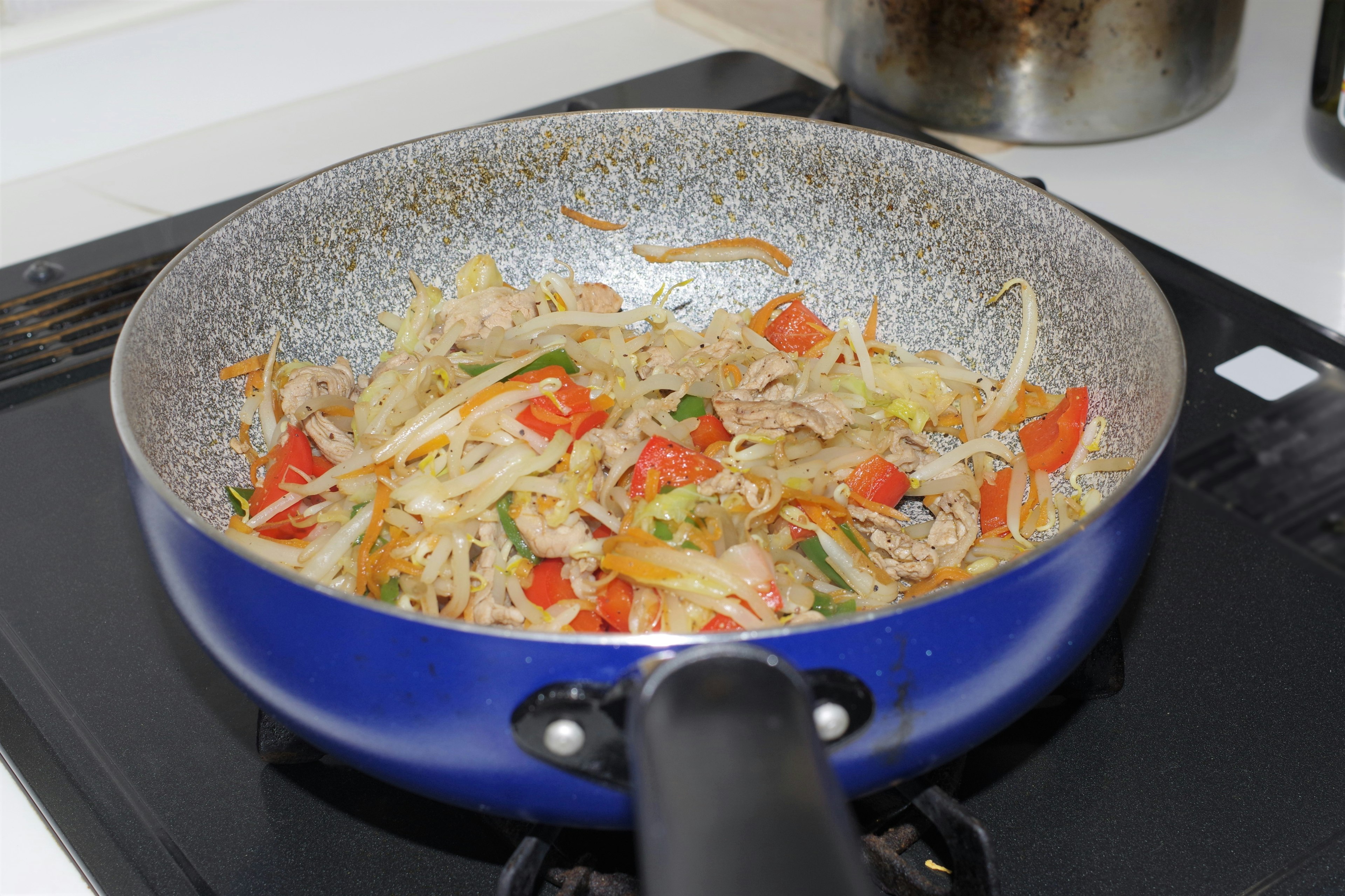 青いフライパンに野菜炒めが入っている