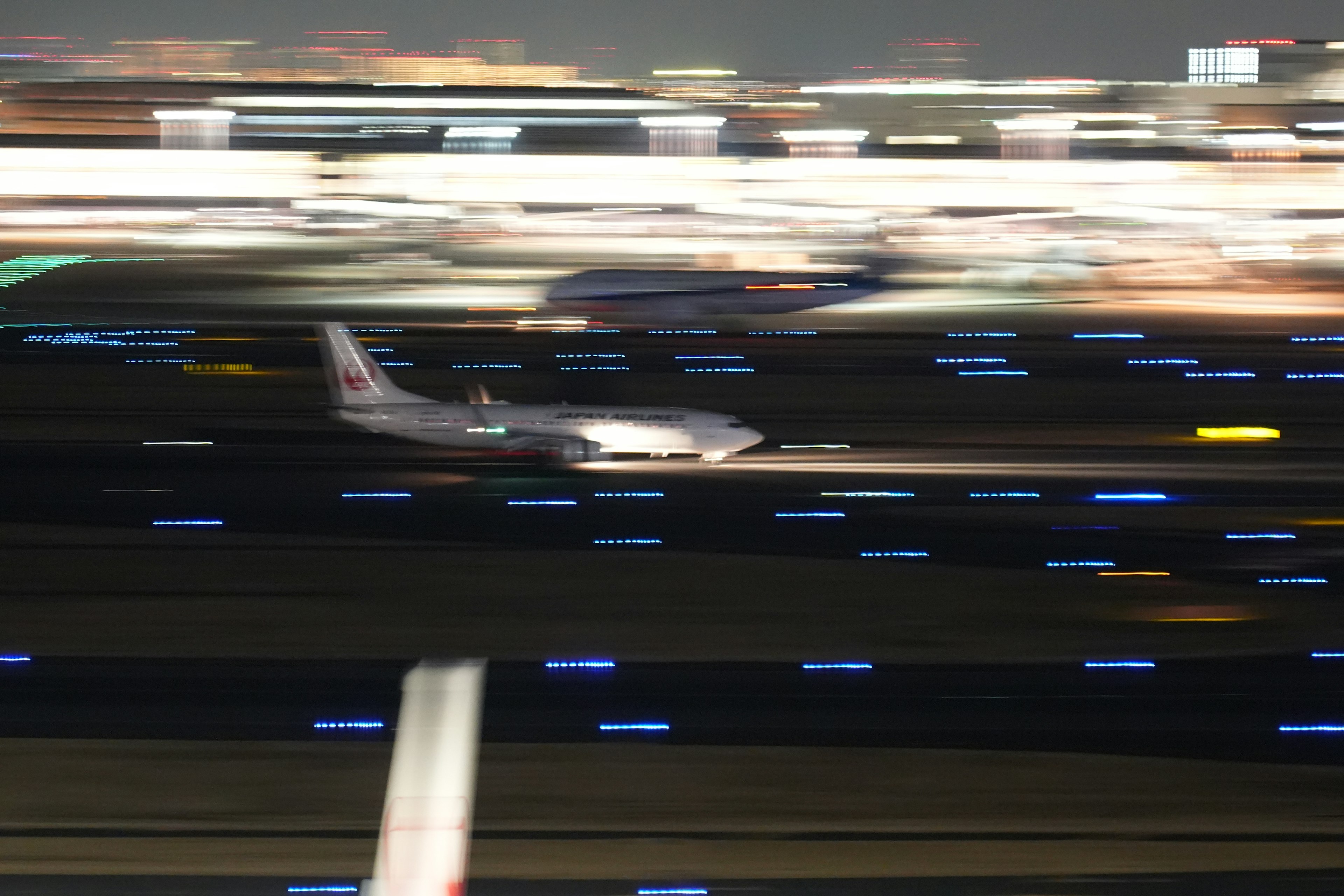 夜の空港で滑走路を滑走する飛行機のぼやけた画像