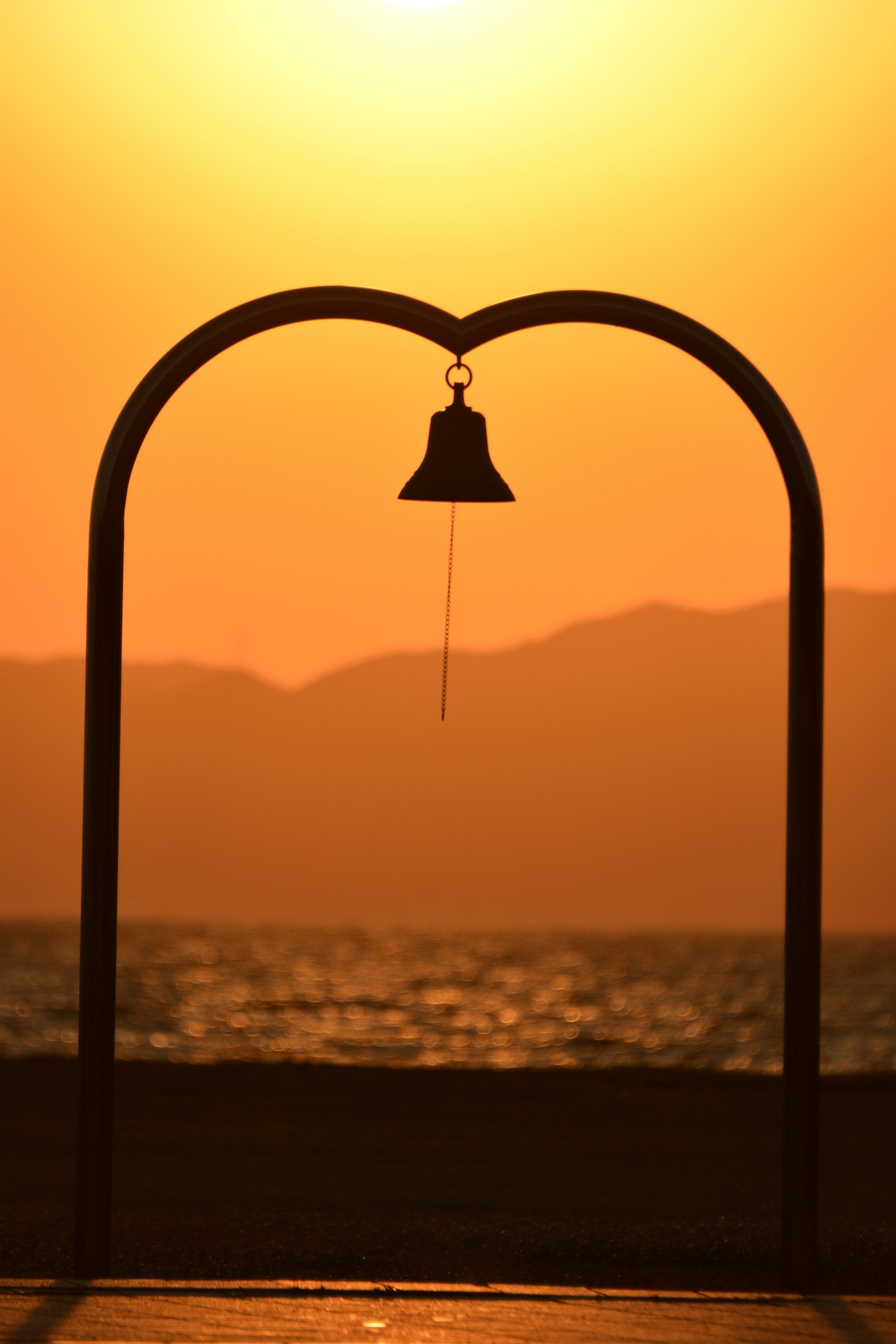 Una hermosa escena con un arco en forma de corazón y una campana contra el atardecer