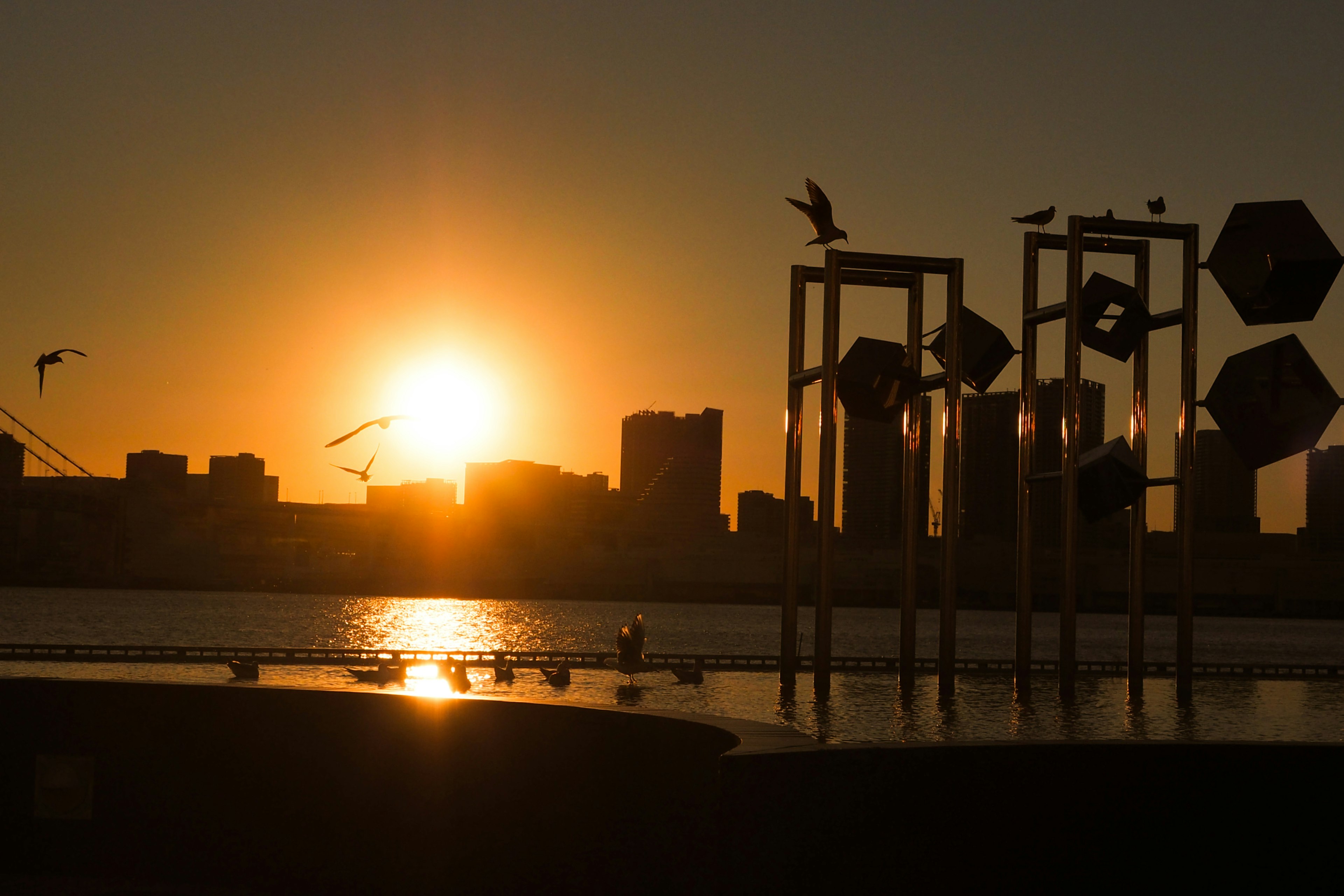 Silhouette di una città al tramonto con riflessi sull'acqua