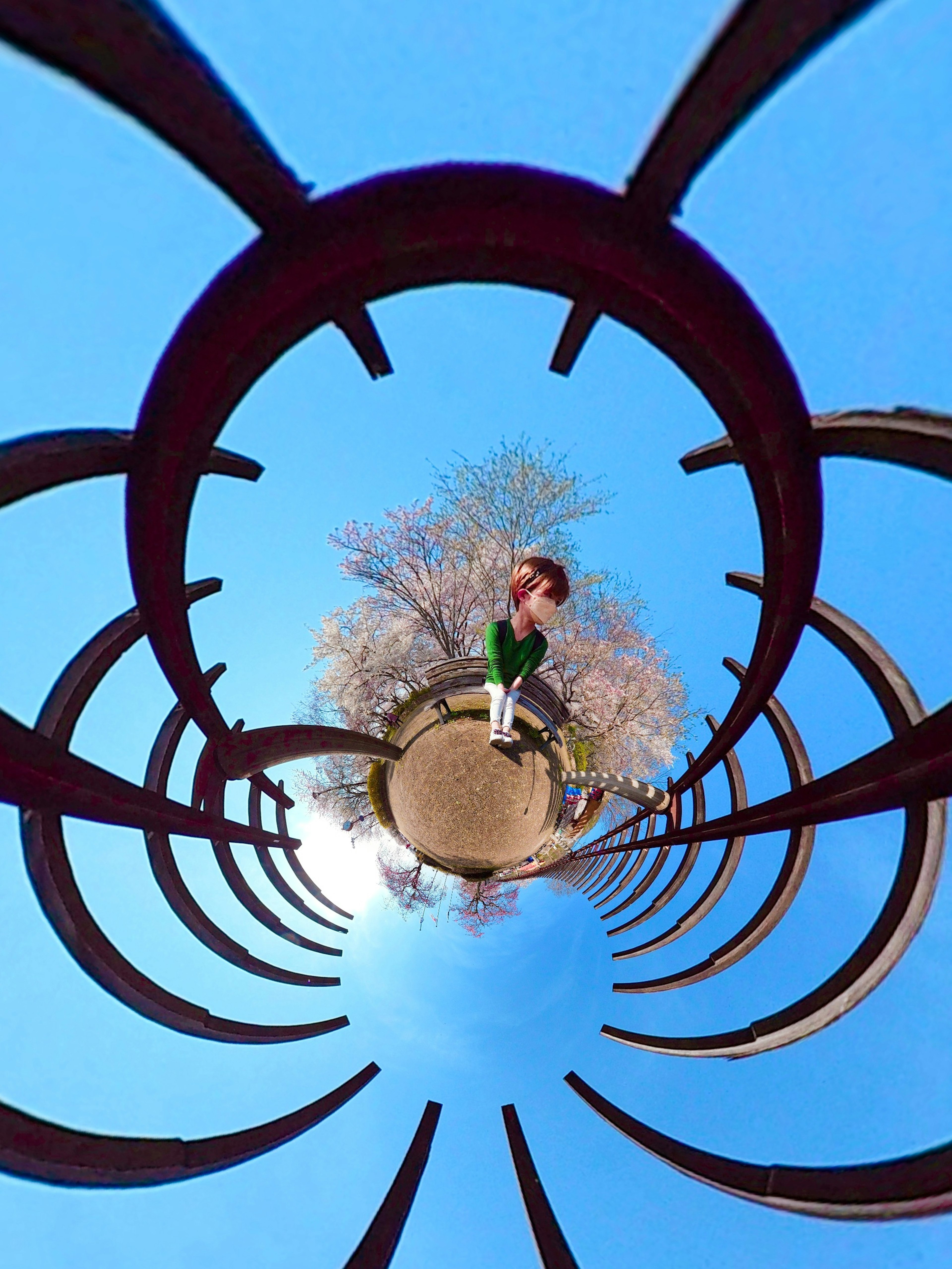 Niño jugando bajo un cielo azul con estructura de anillos metálicos