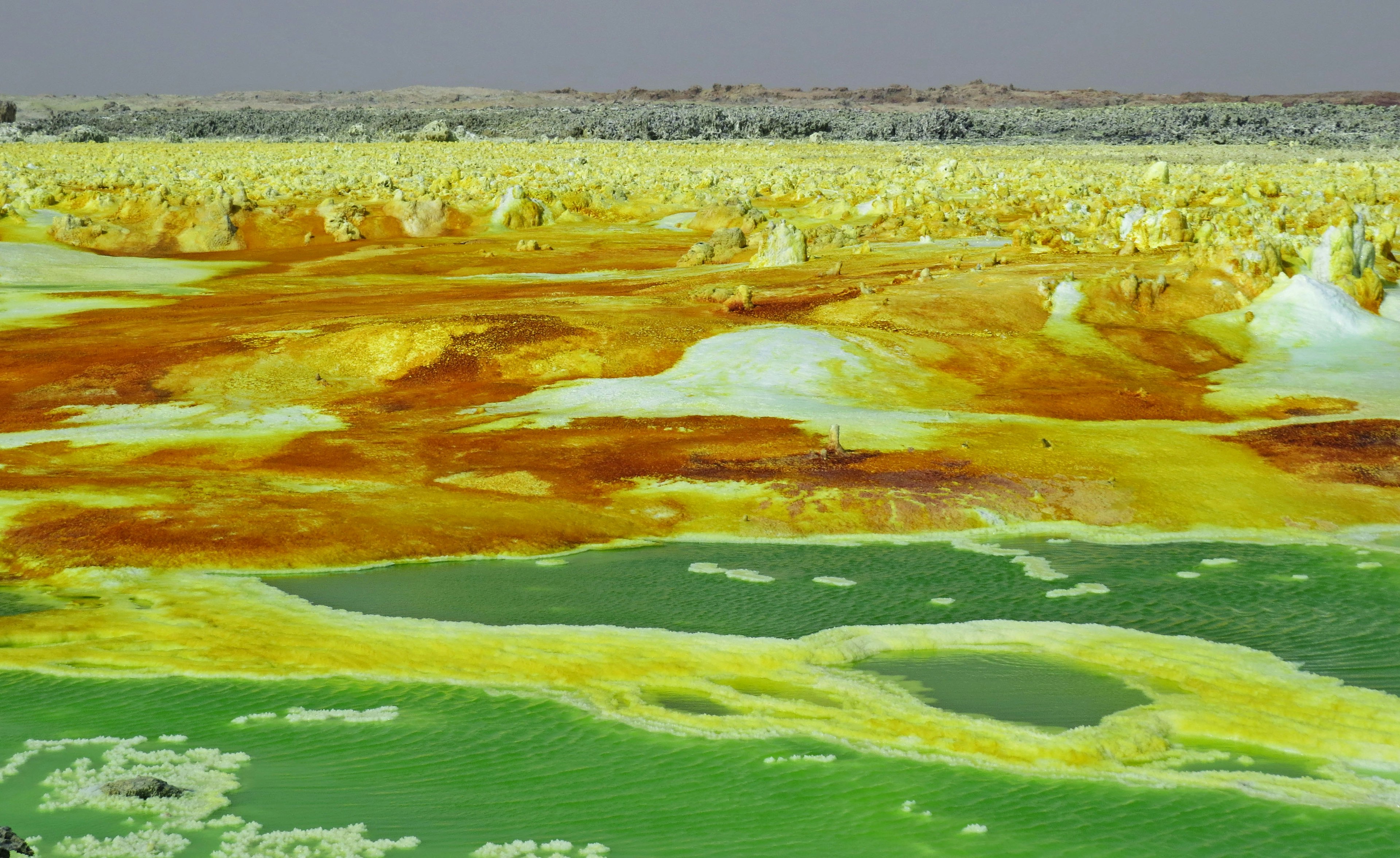 Buntes Landschaftsbild mit leuchtend gelben und grünen Formationen und Teichen