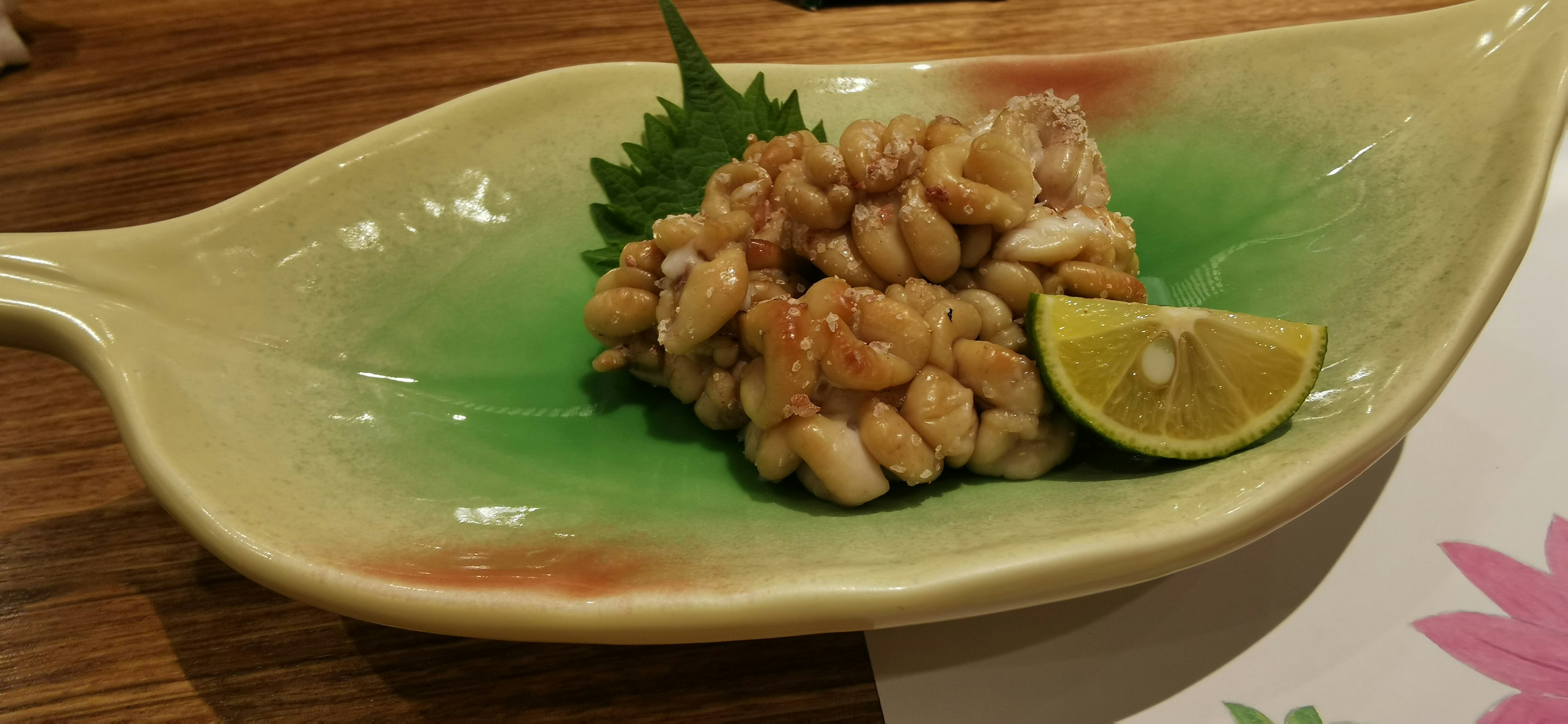 Fresh sashimi served on a green dish with a slice of lime