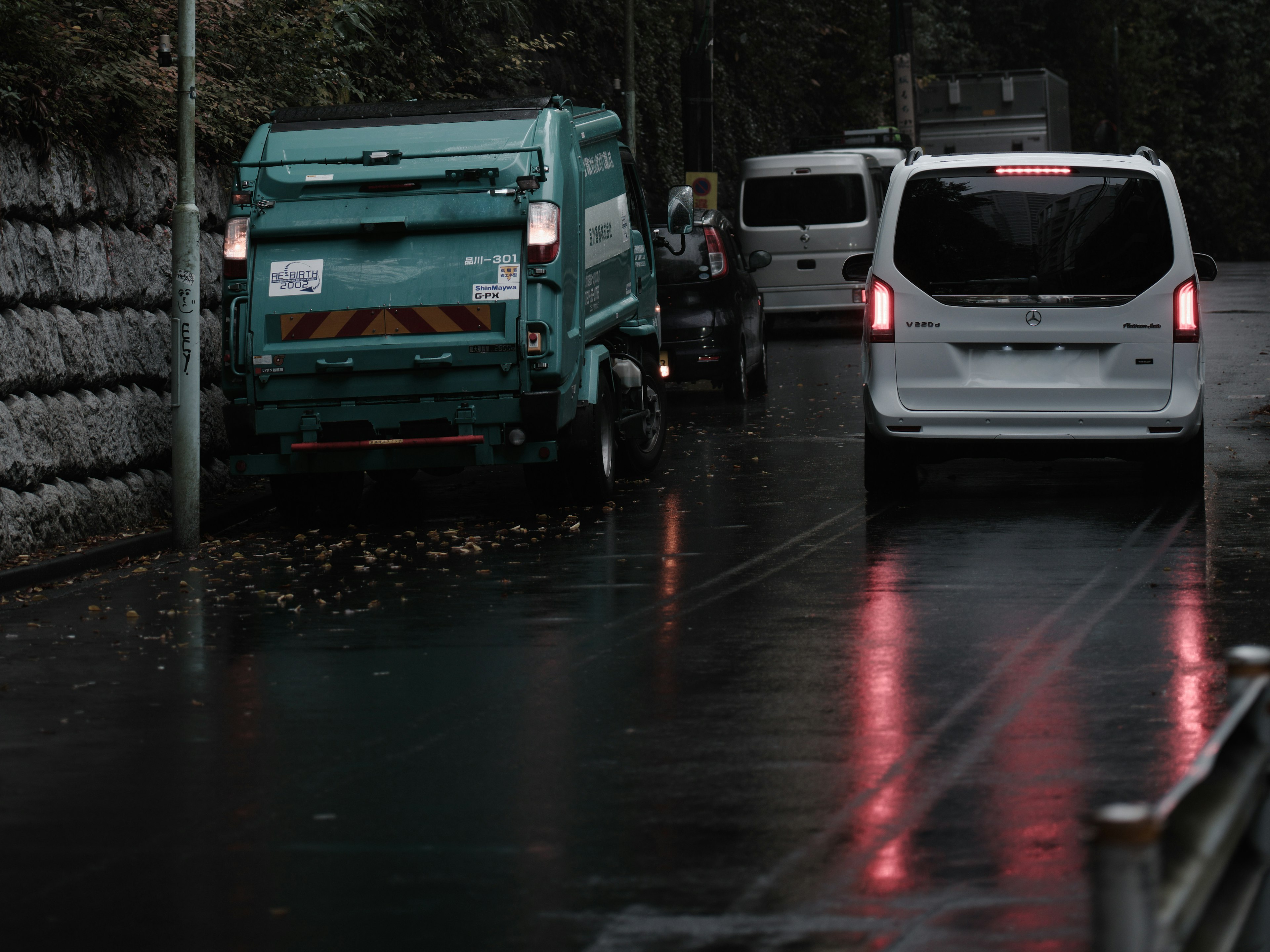 Camion poubelle et fourgon blanc garés sur une route humide