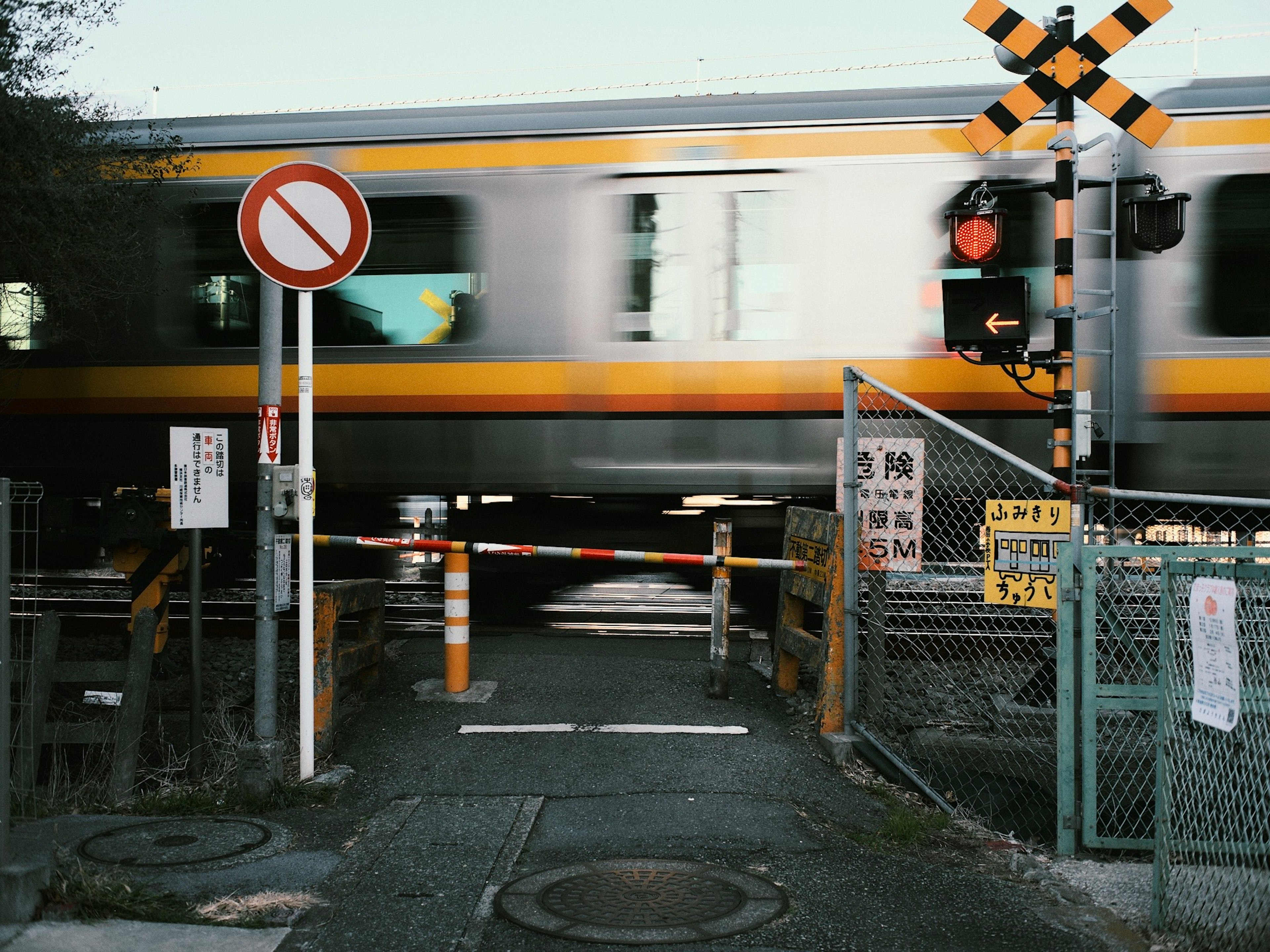 A train passing through a level crossing with warning signs and a gate visible