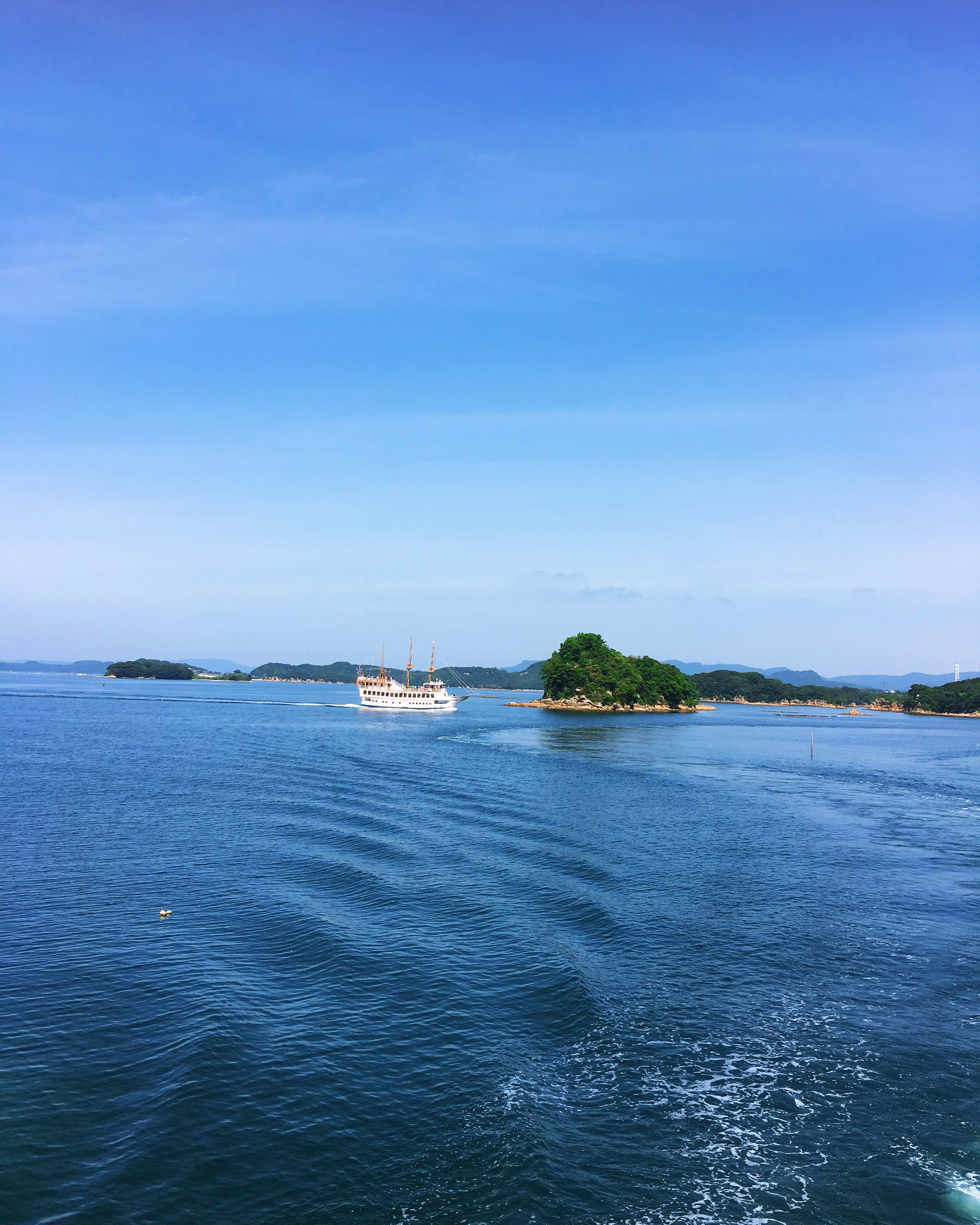 Pemandangan laut biru dengan pulau-pulau kecil di bawah langit cerah