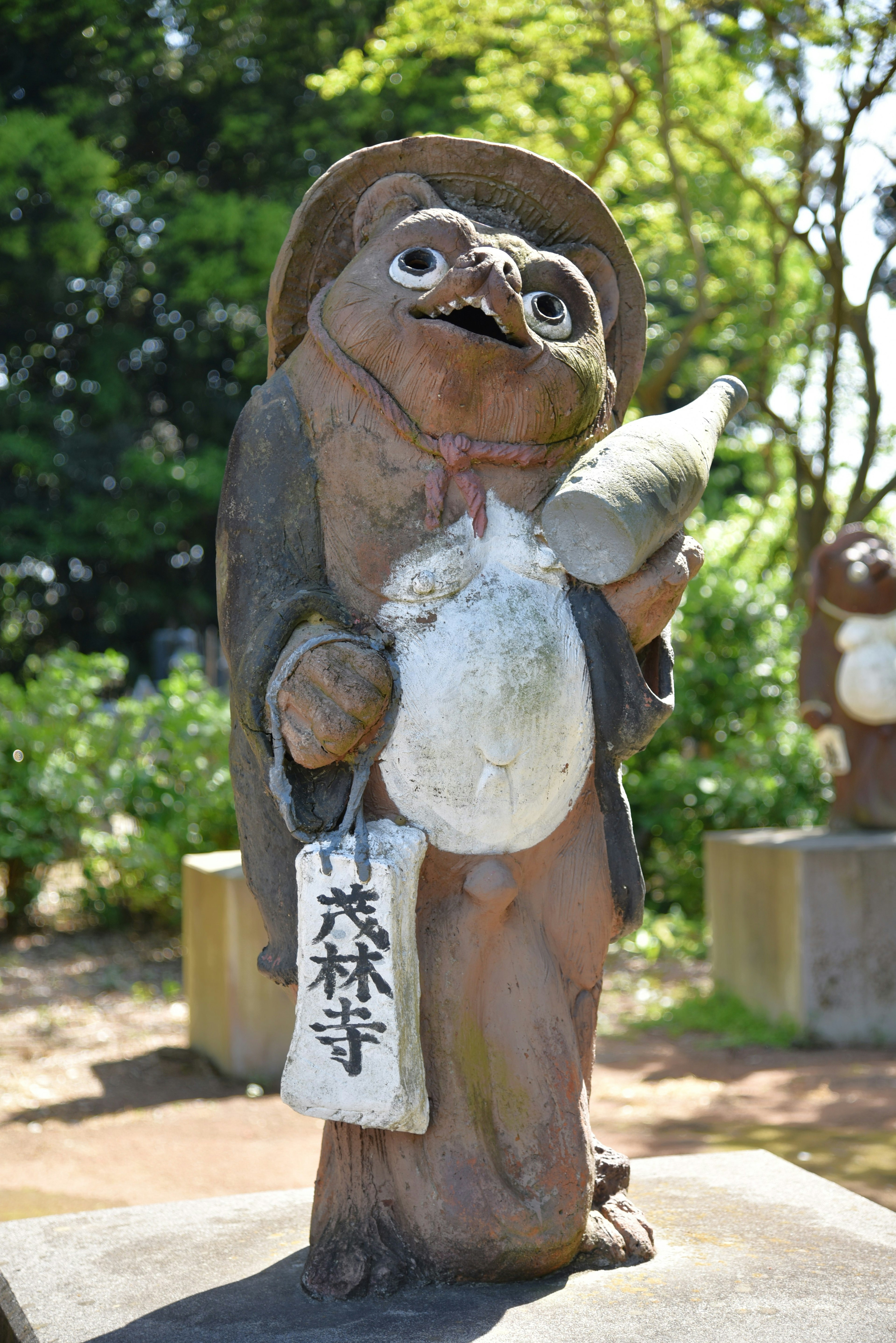 Estatua de tanuki con un sombrero y un pez