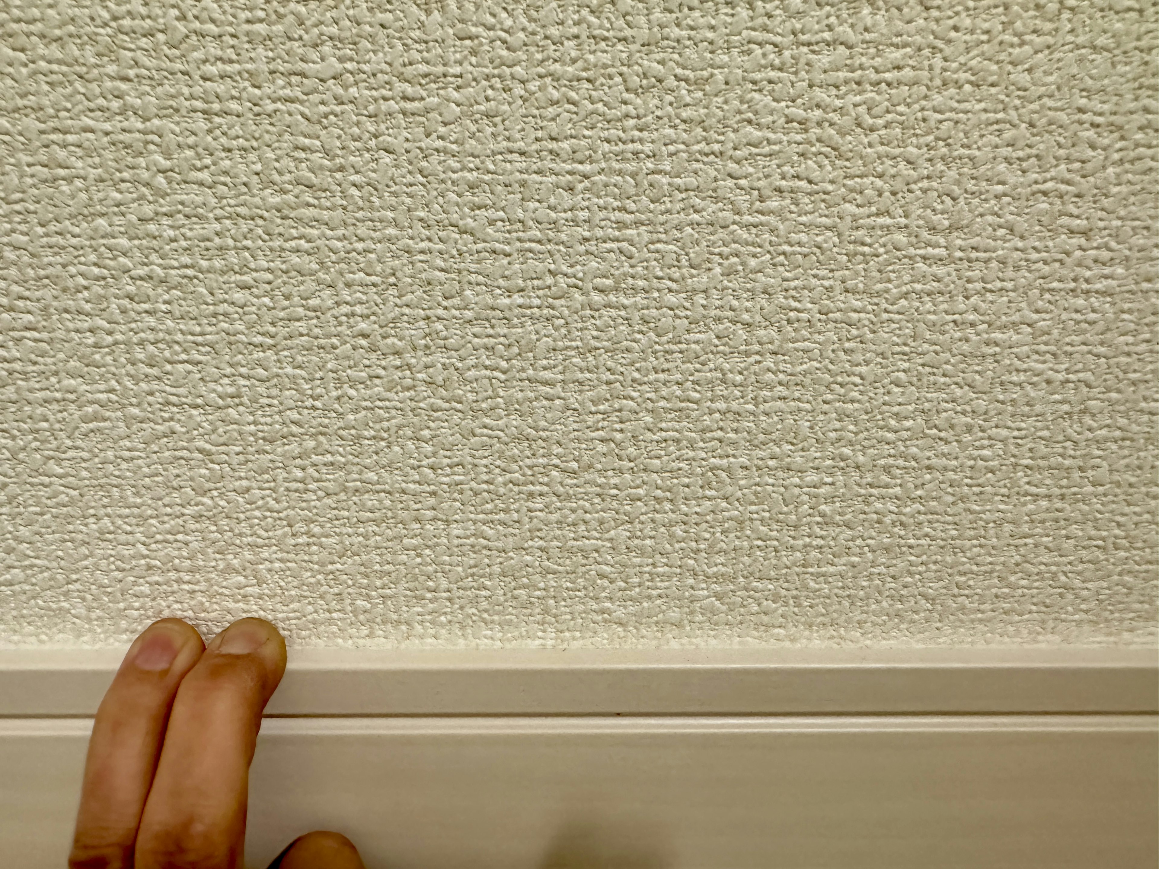 Textured wall with hand touching and molding at the bottom