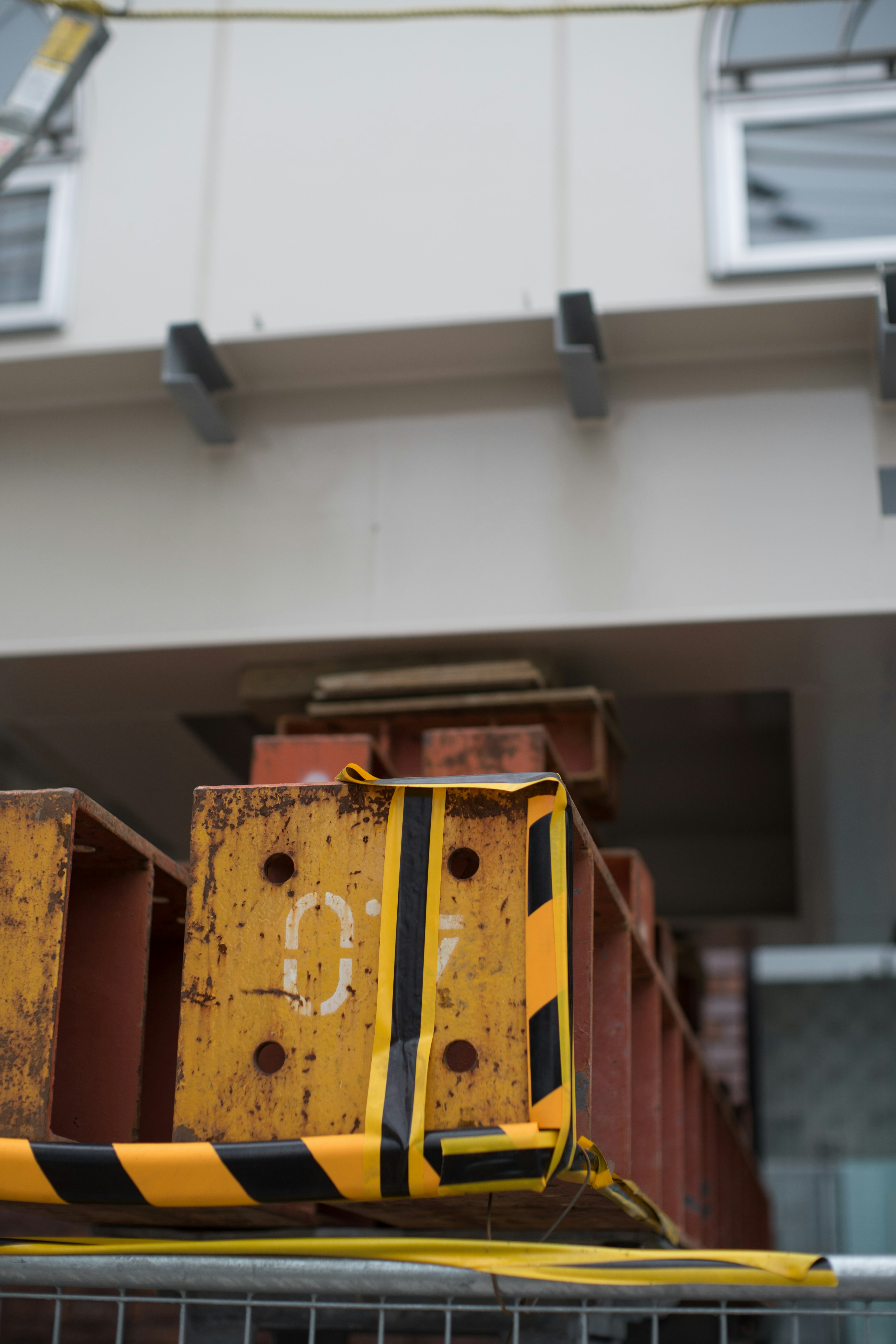 Trave in acciaio arancione sotto un edificio con strisce di sicurezza gialle e nere